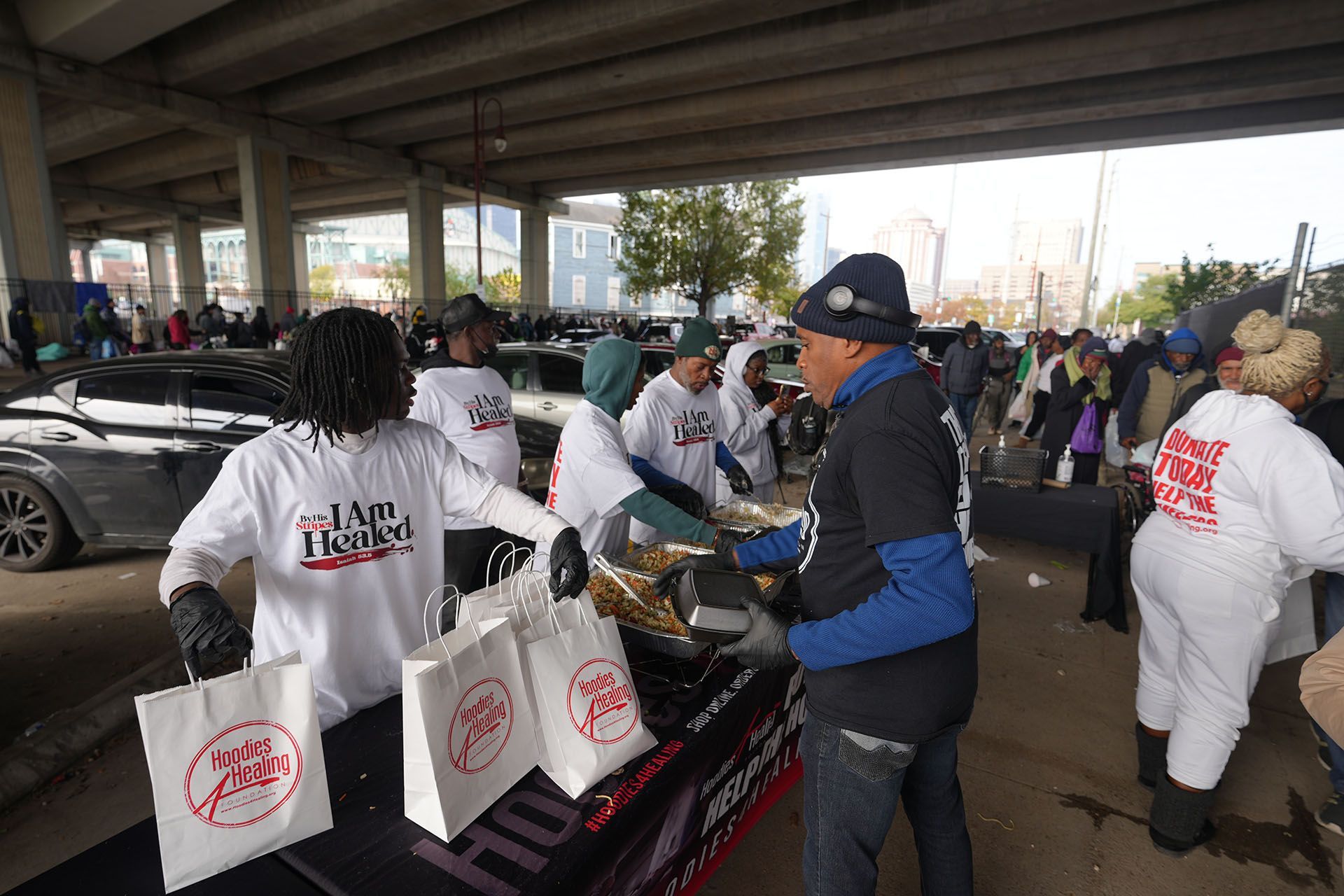 A group of people are standing around a table with bags of food.