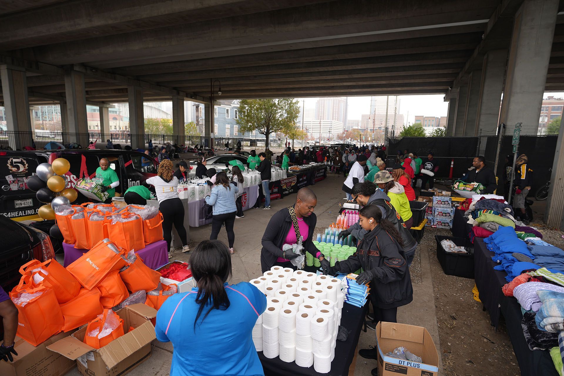 A group of people are standing around a table with rolls of toilet paper.