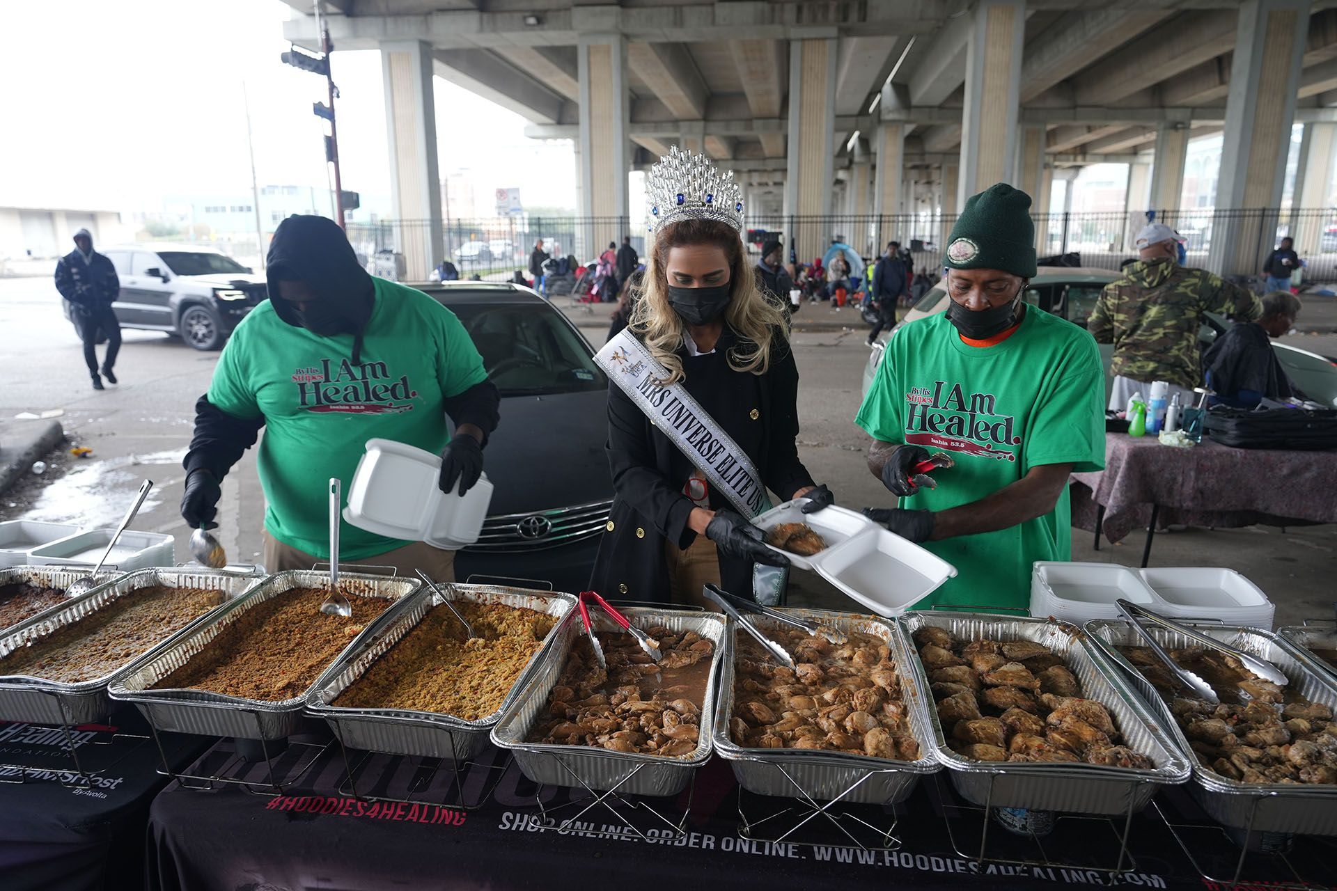 A group of people are standing around a table with trays of food.