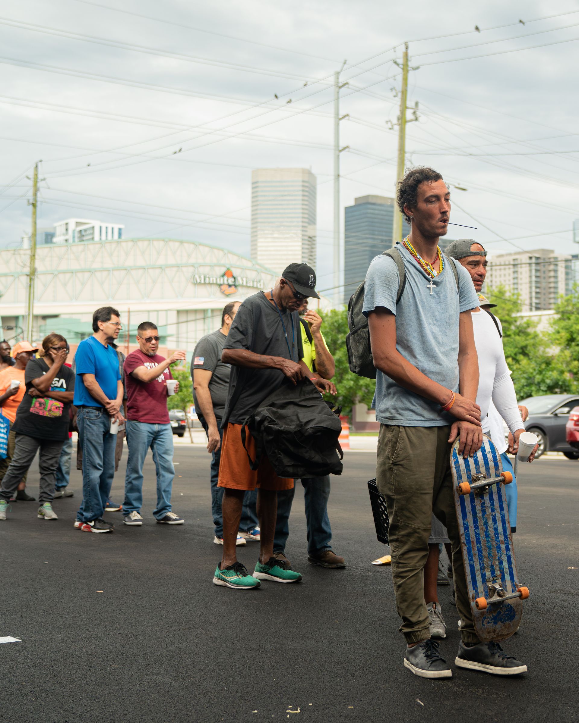 A group of people standing on a street with one man holding a skateboard