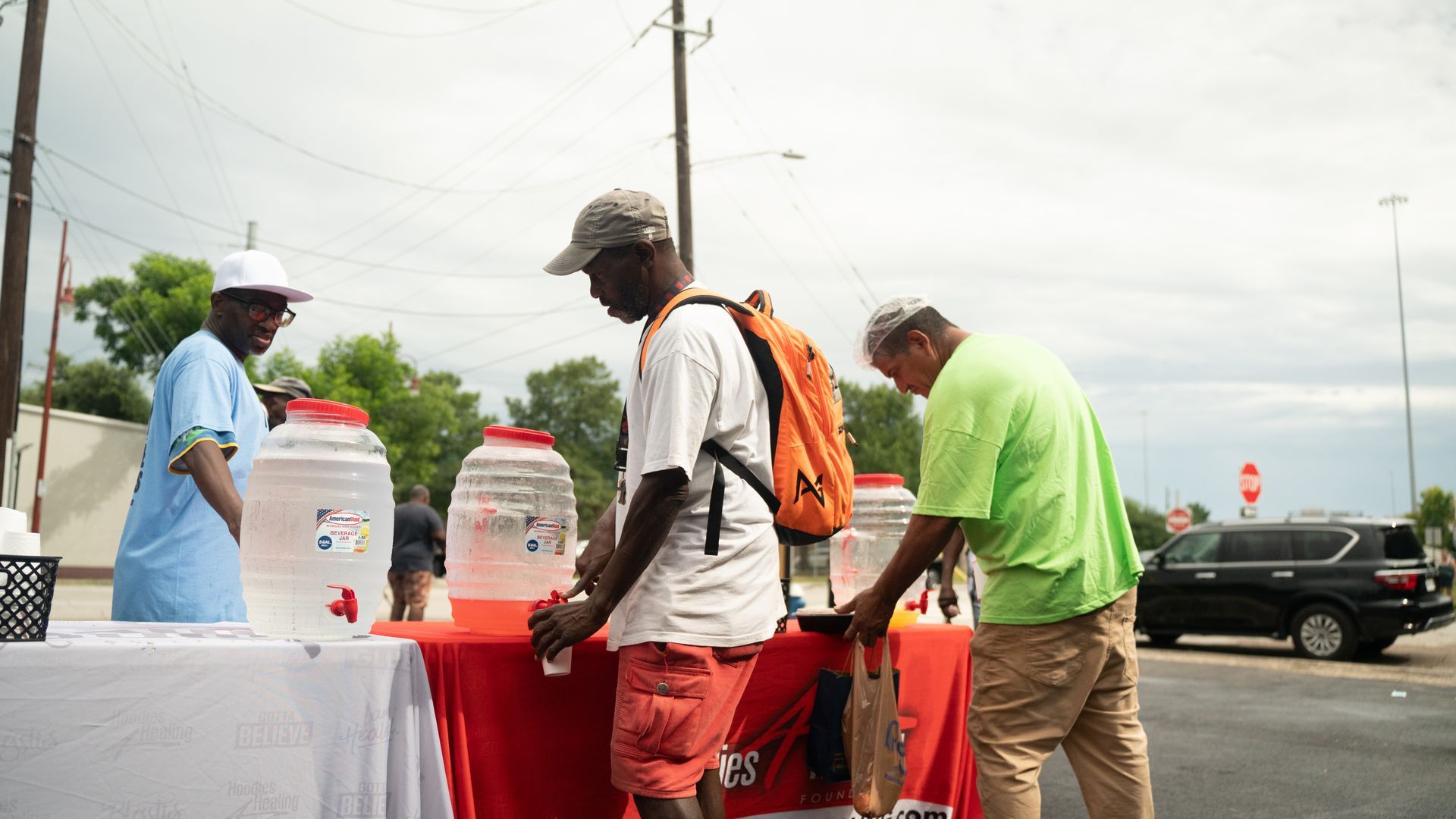 A group of men are standing around a table in a parking lot.