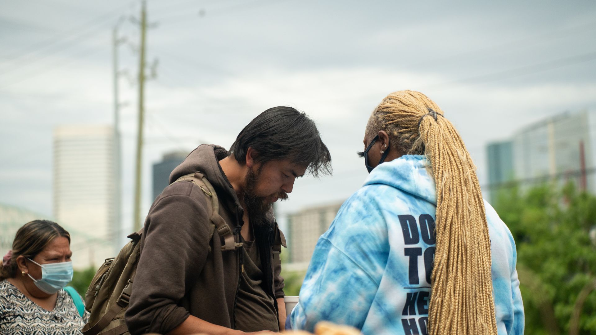 A man is talking to a woman in a blue tie dye hoodie.