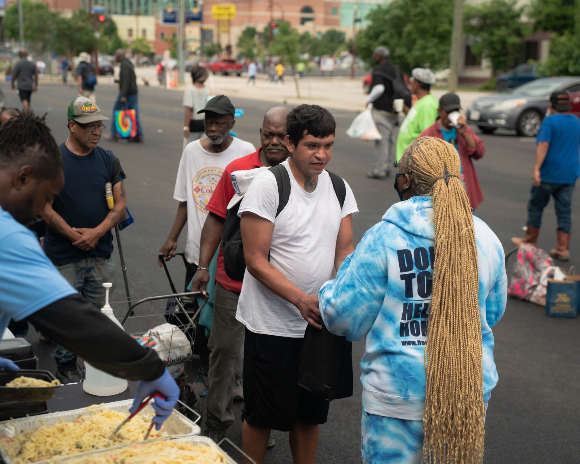 A group of people are standing on a street talking to each other.