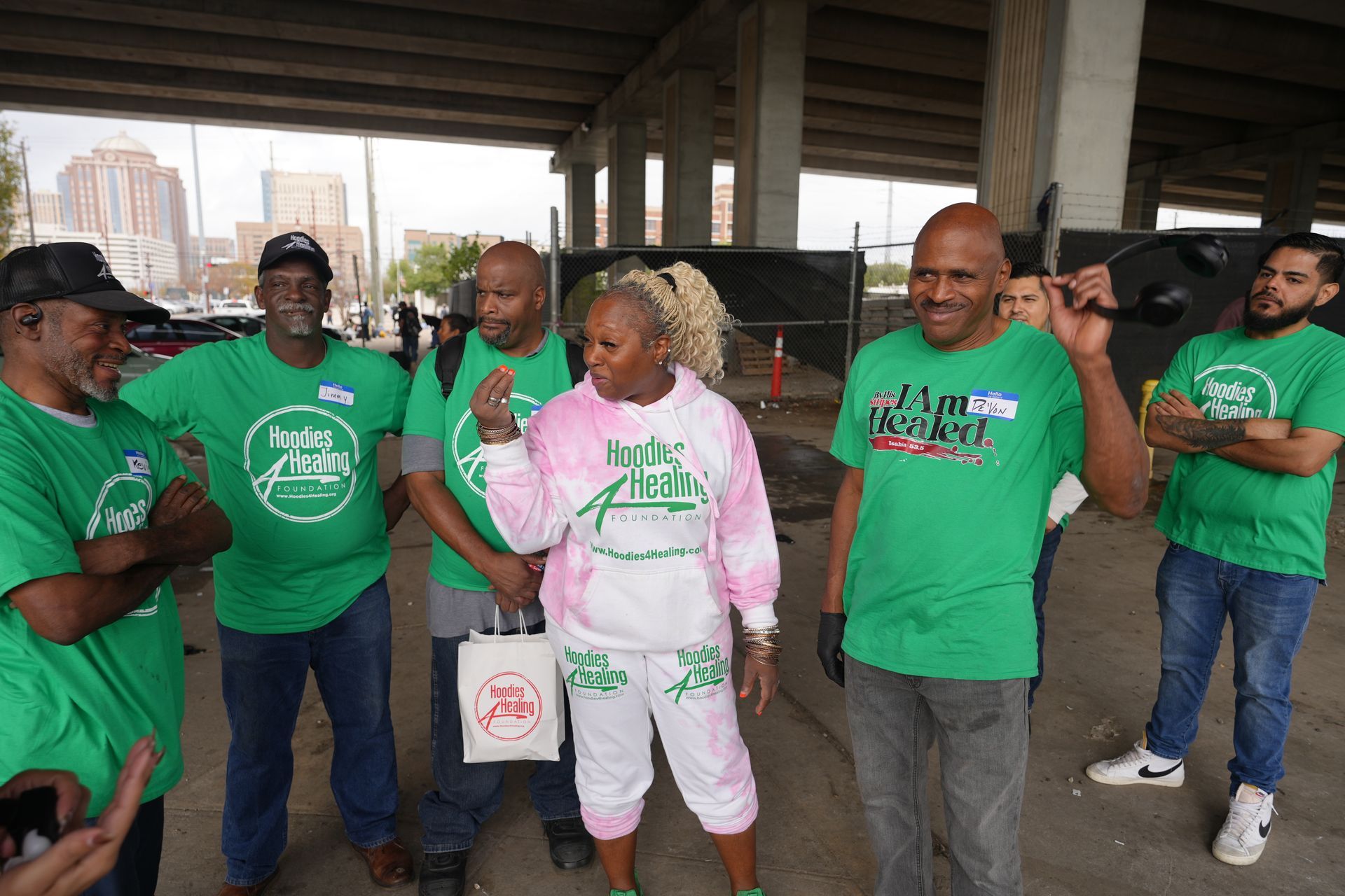 A group of people wearing green shirts are standing in a circle.