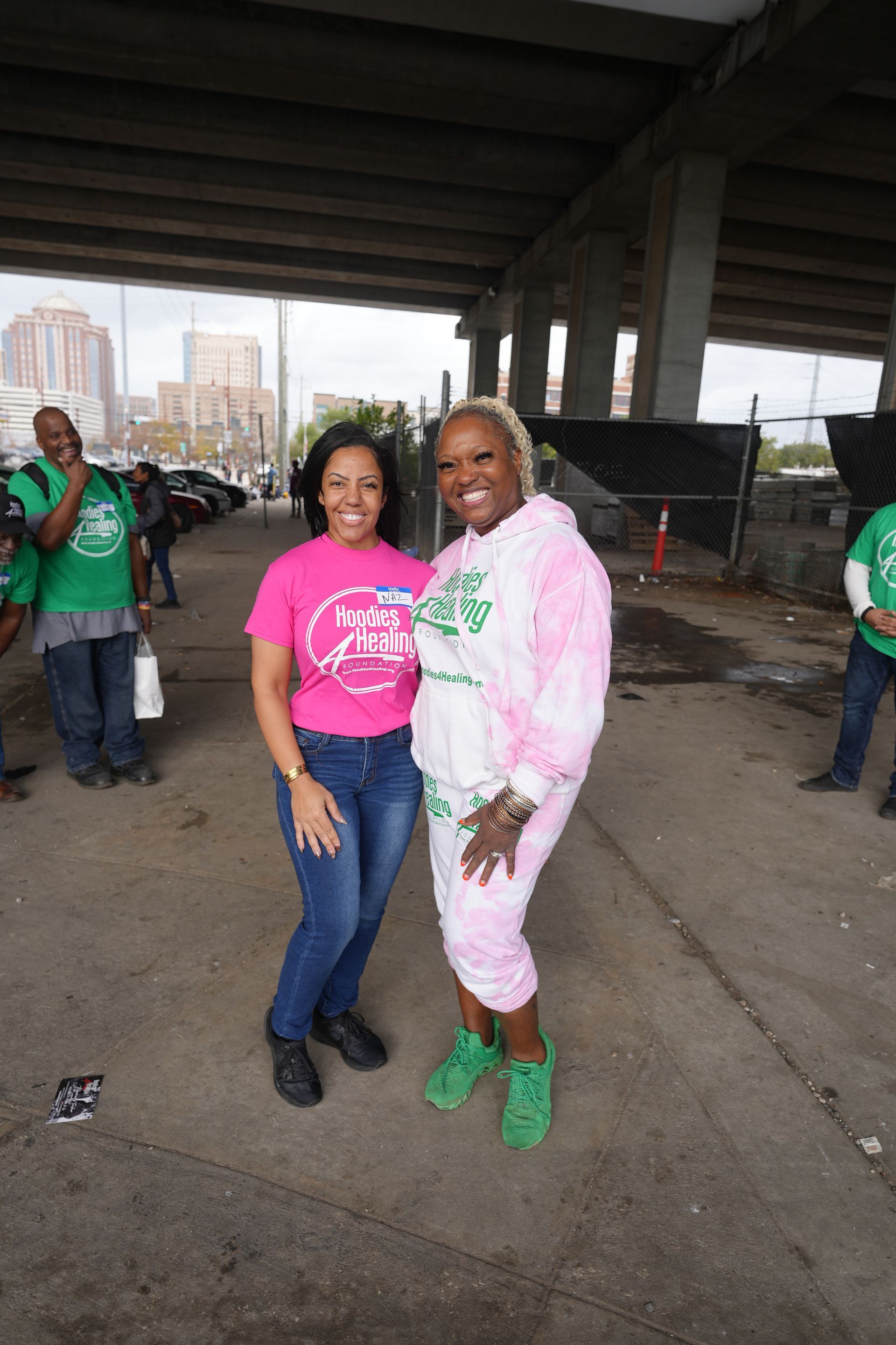 Two women are posing for a picture under a bridge.