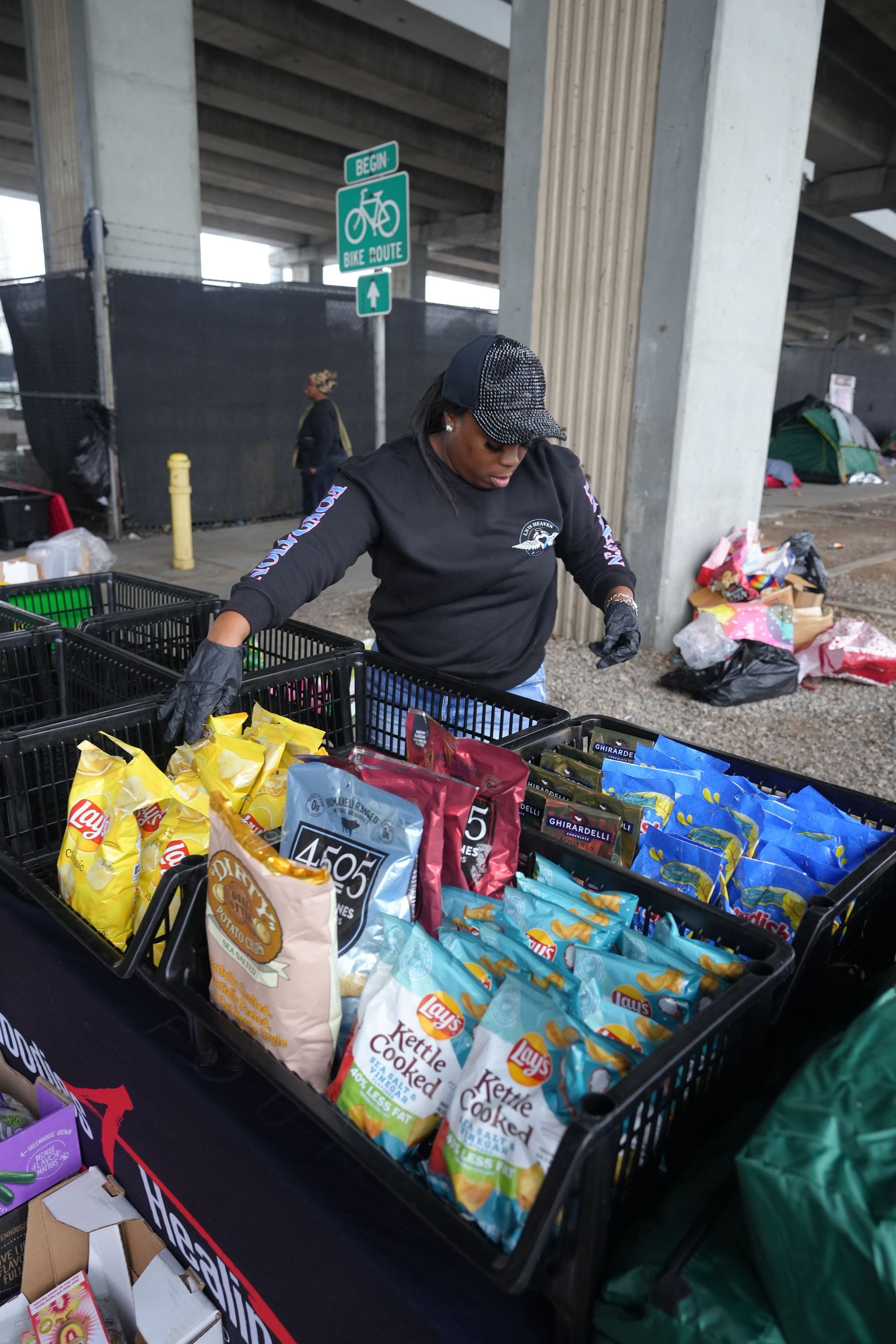 A woman is standing in front of a table filled with bags of food.