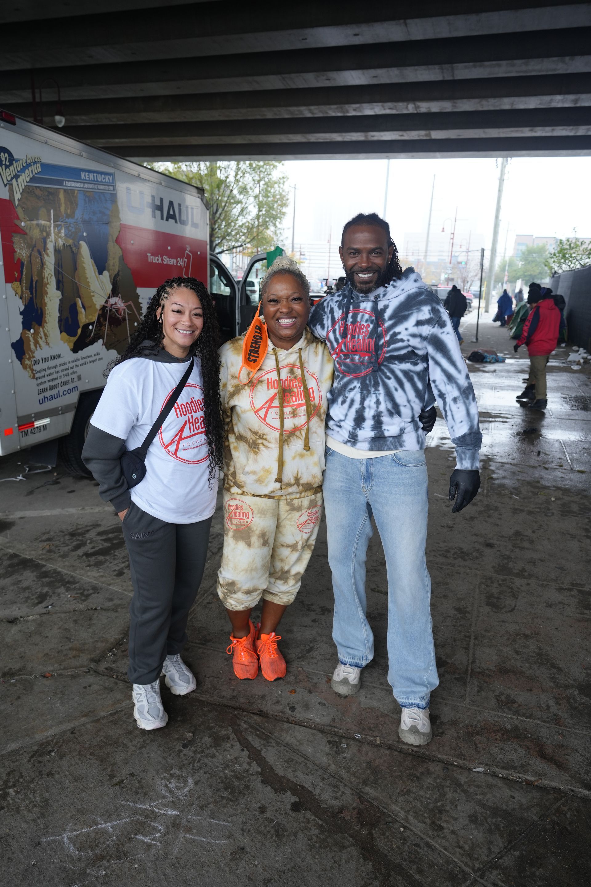 A man and two women are posing for a picture under a bridge.