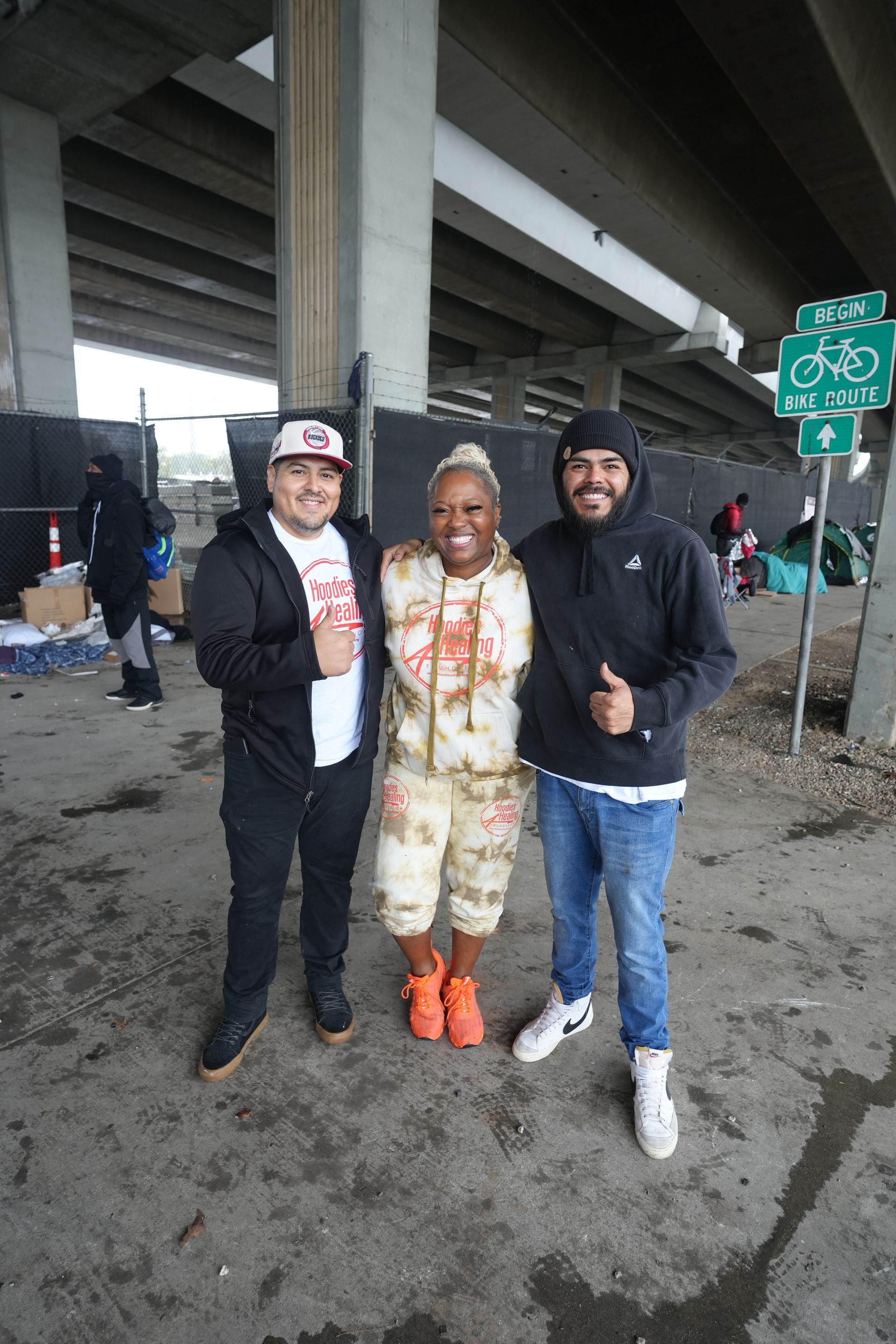 Three people are posing for a picture under a bridge.