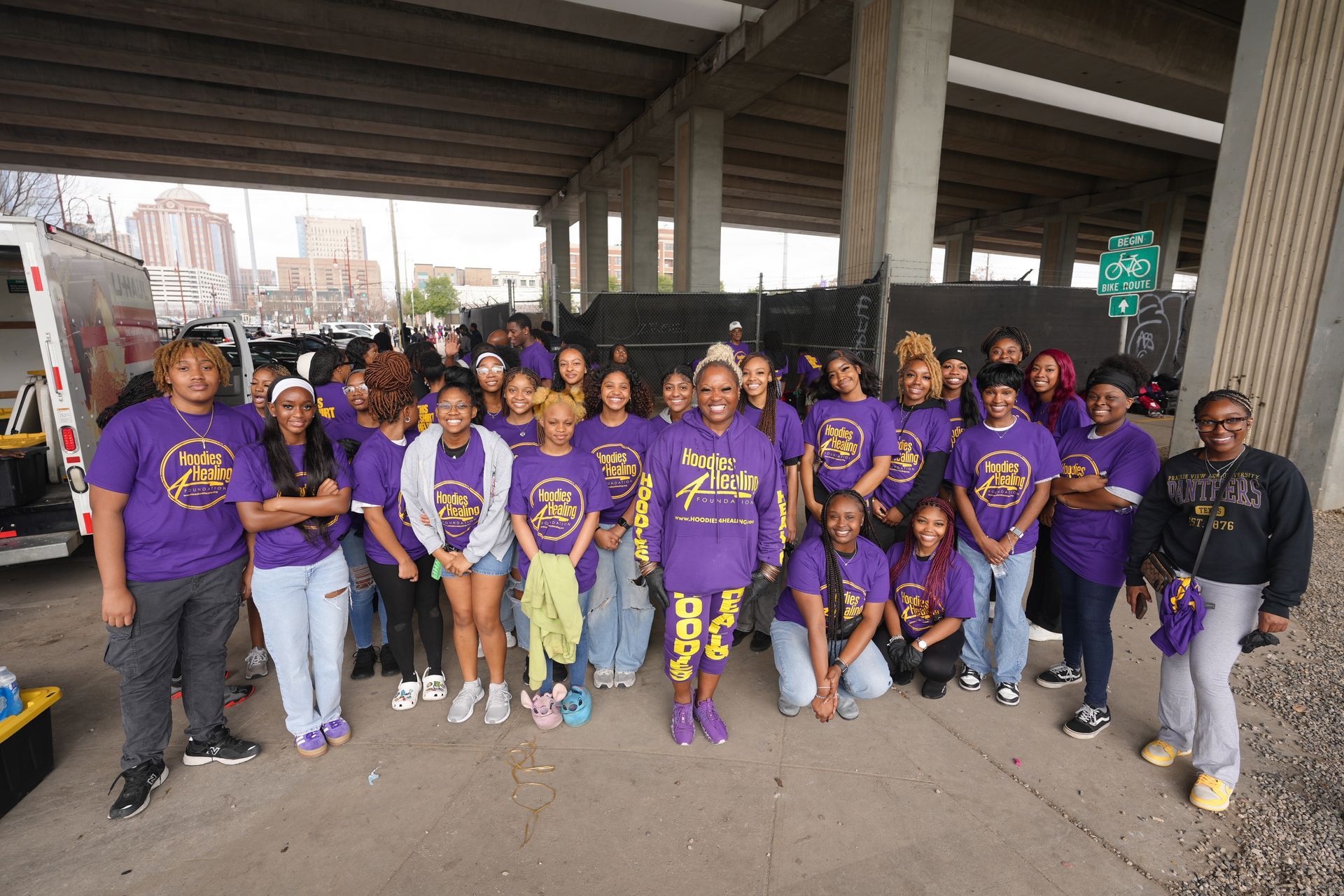 A group of people are standing around a table under a bridge.