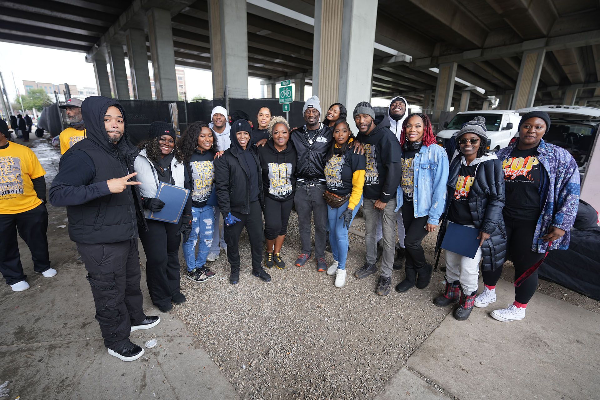 A group of people are posing for a picture under a bridge.