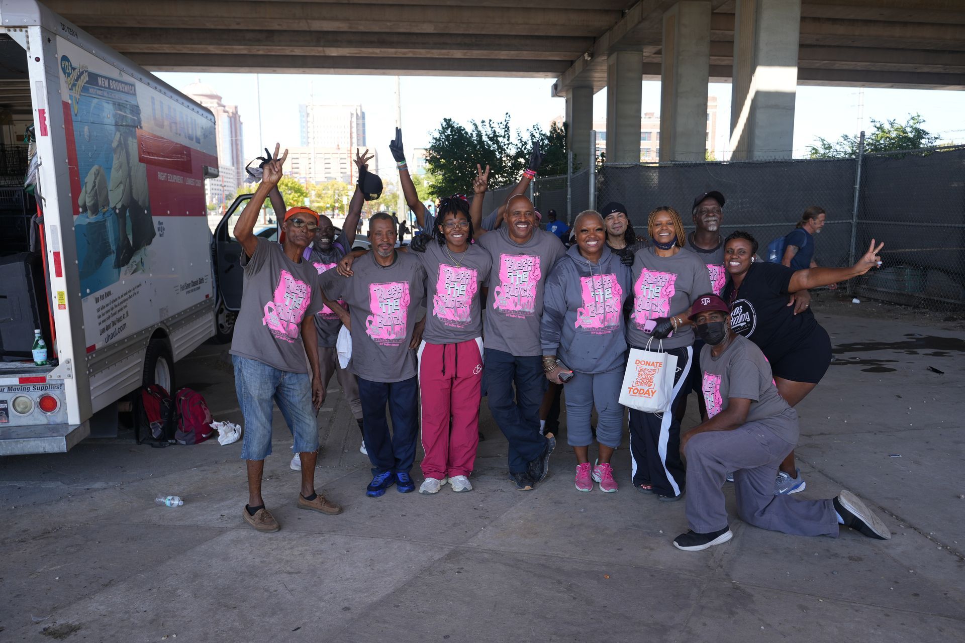 A group of people are posing for a picture under a bridge.