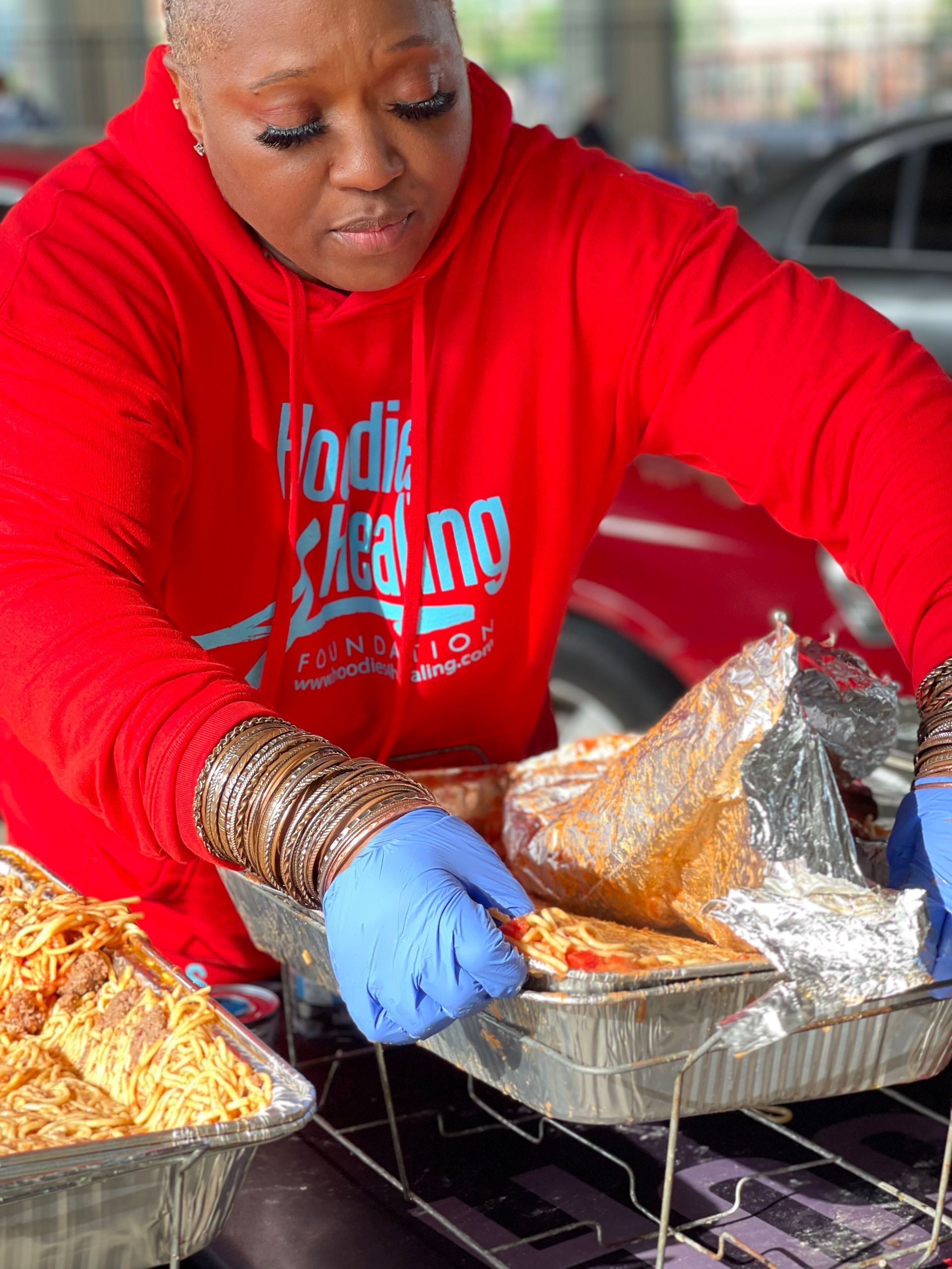 A woman in a red hoodie is preparing food