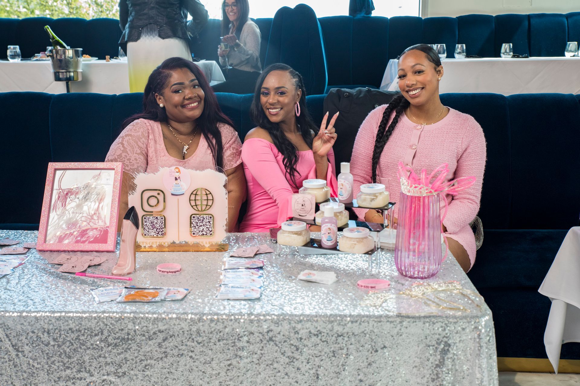 Three women in pink sweaters are sitting at a table.