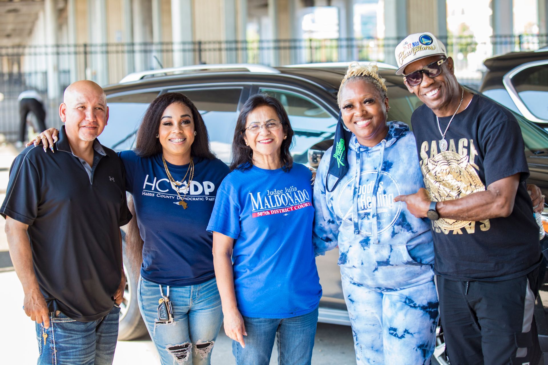 A group of people are posing for a picture in front of a car.