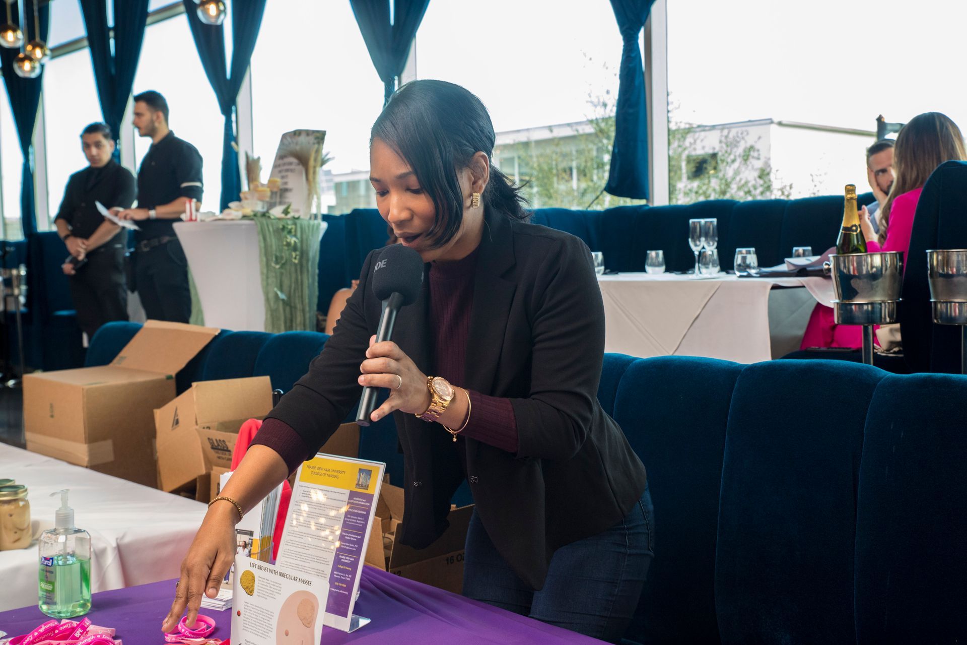 A woman is standing at a table holding a microphone.