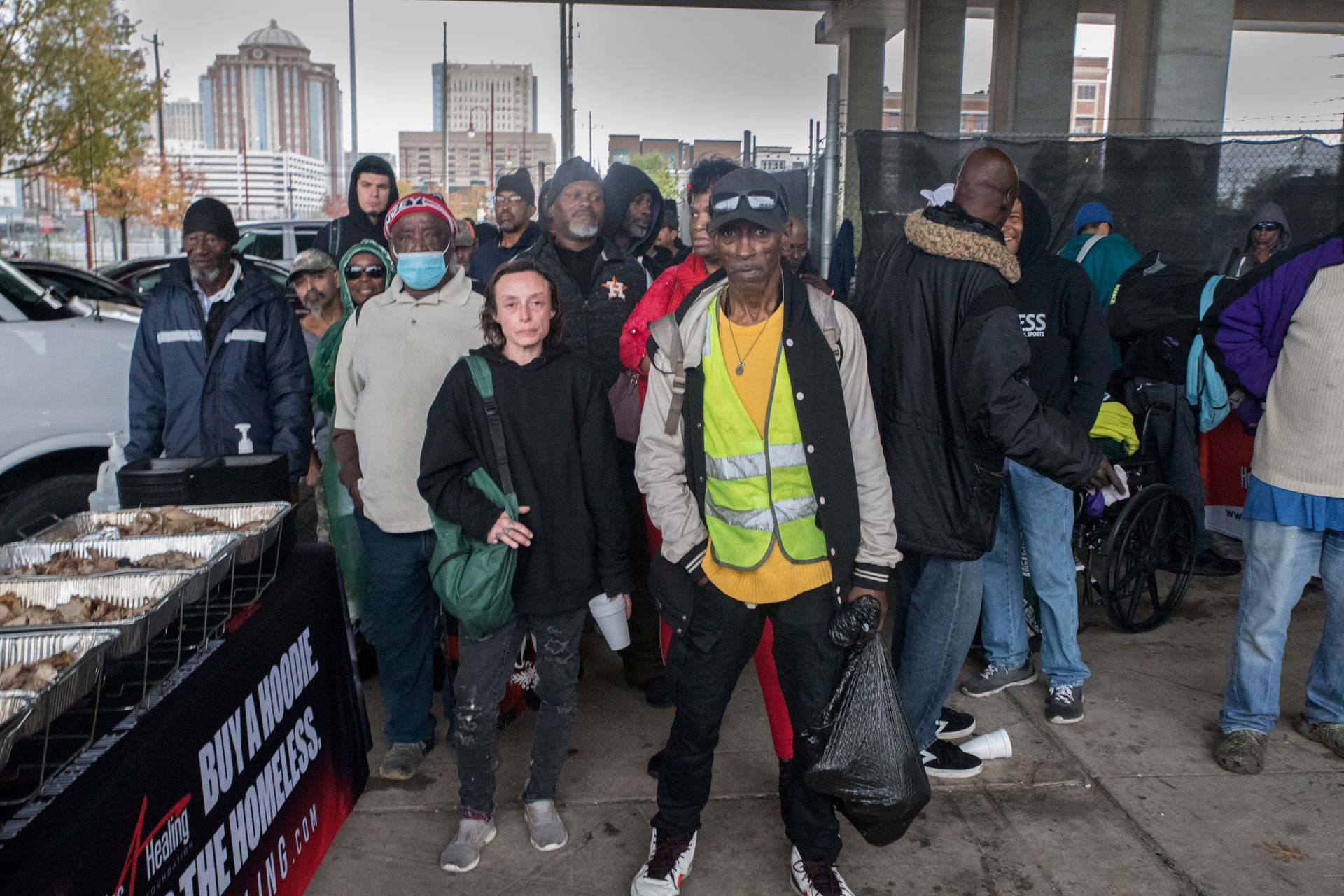 A group of people are standing in front of a table with food.