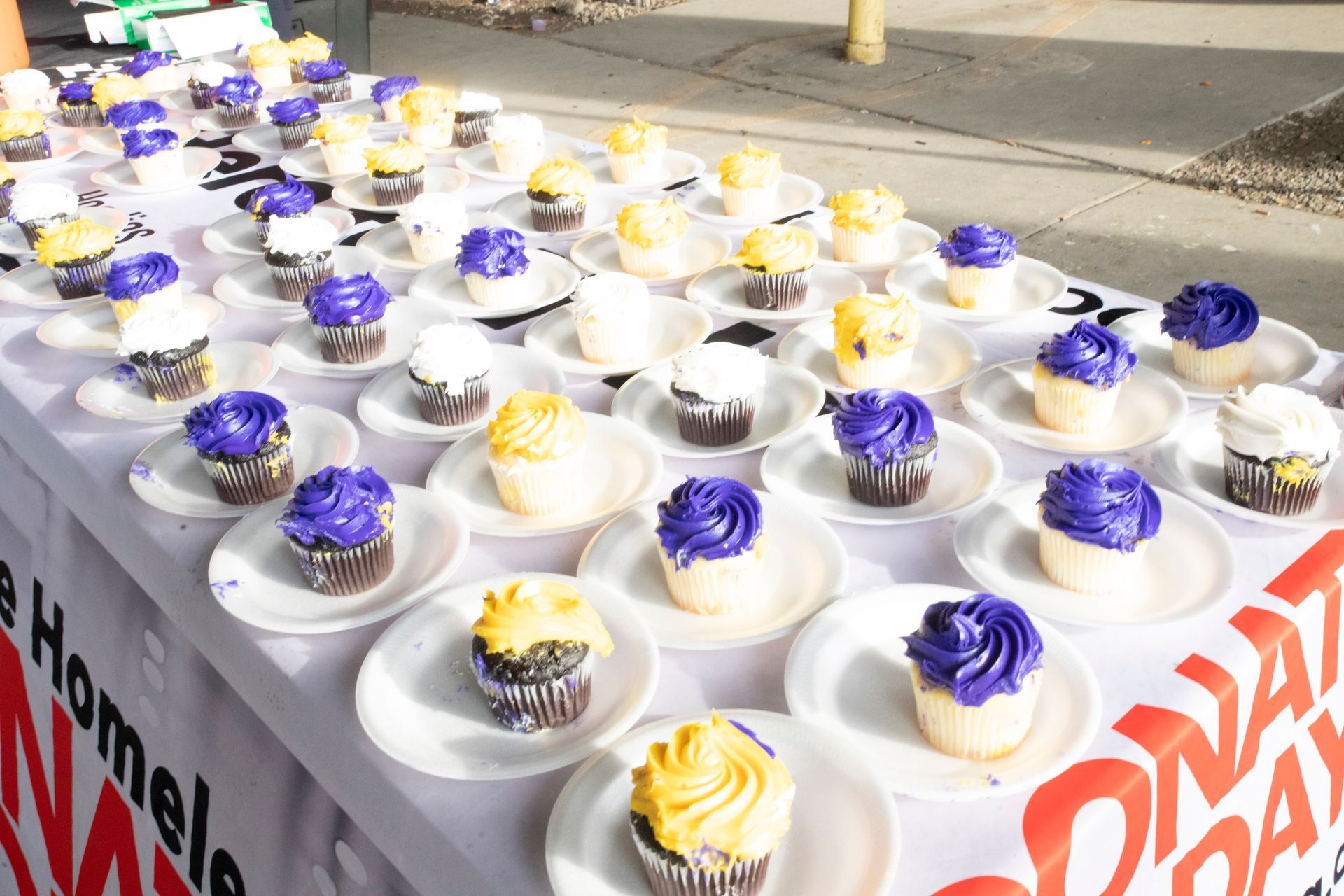 A table full of cupcakes with purple and yellow frosting