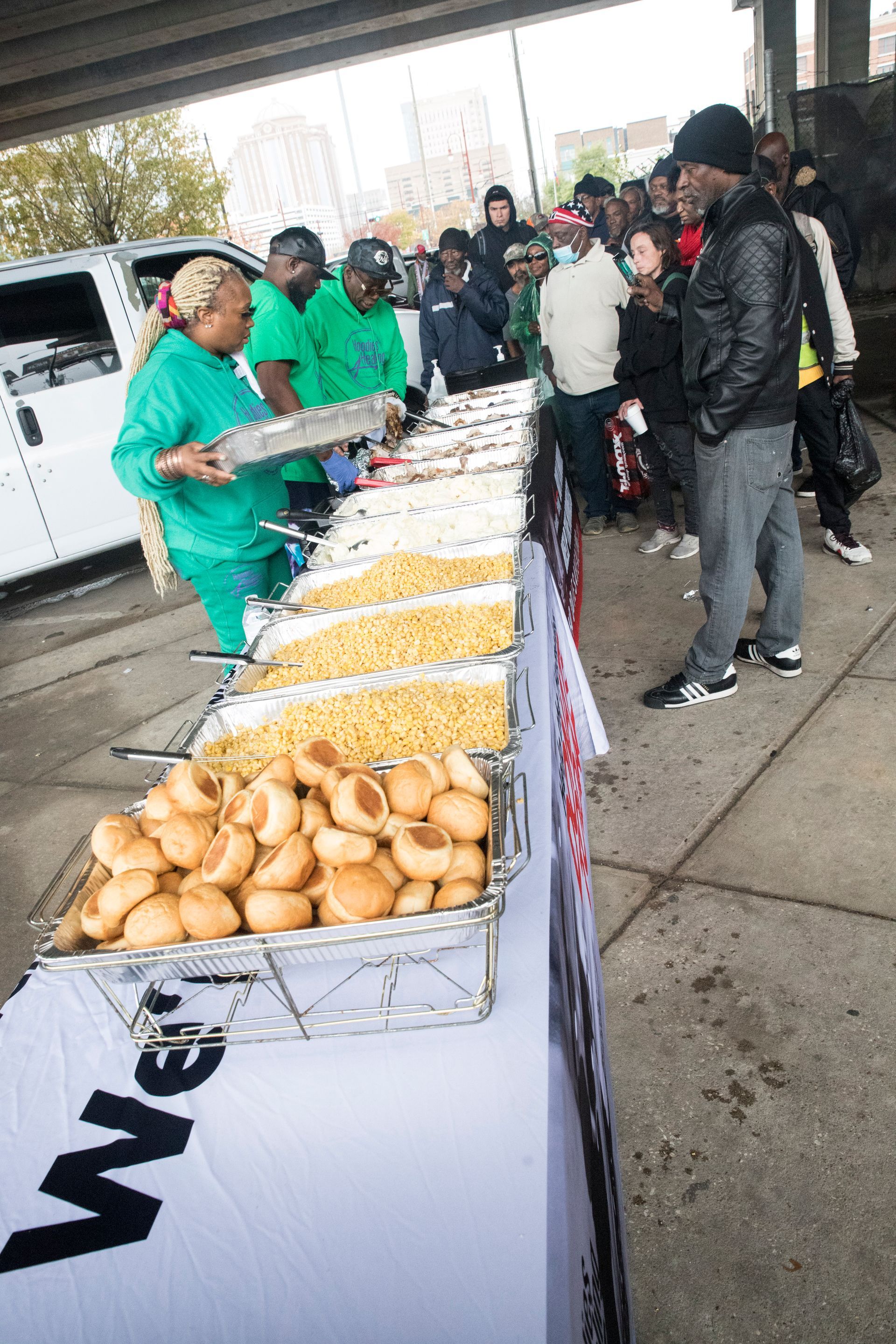 A group of people are standing around a table filled with food.
