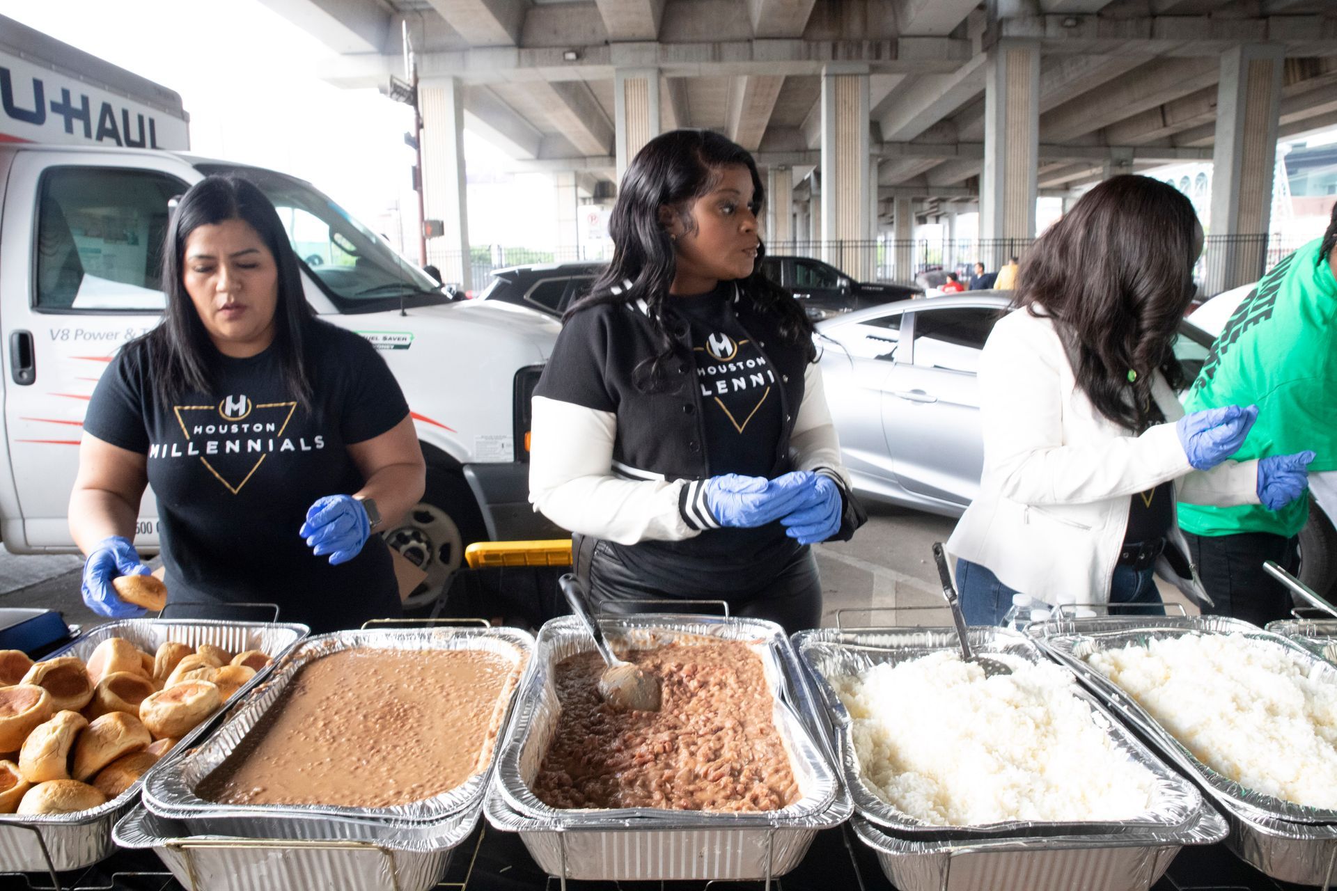 A group of women are standing around a table with trays of food.