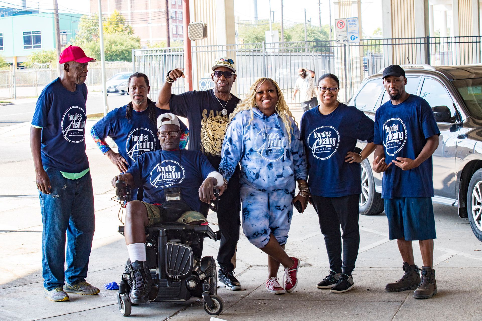 A group of people are posing for a picture with a man in a wheelchair.