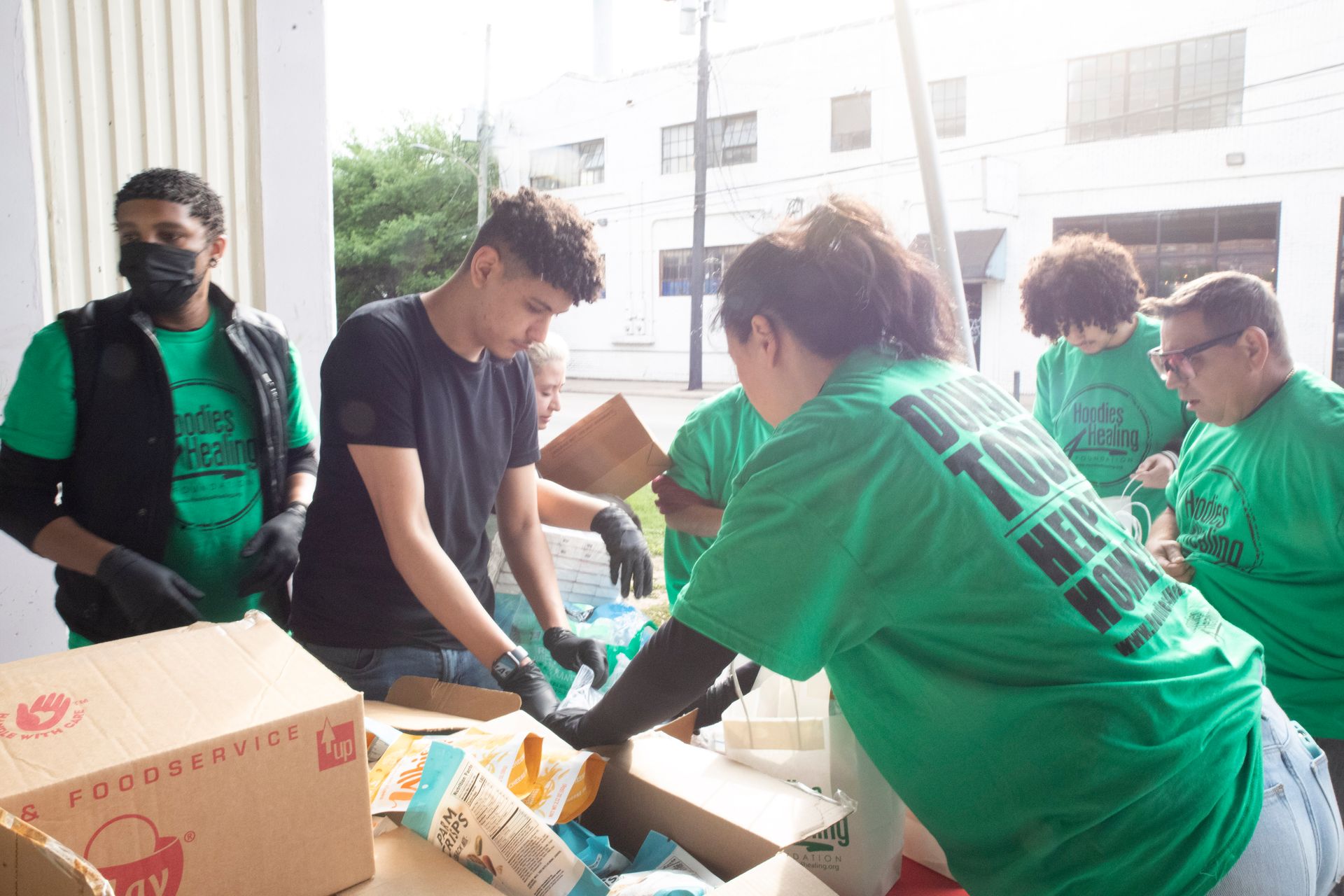 A group of people in green shirts are packing boxes.