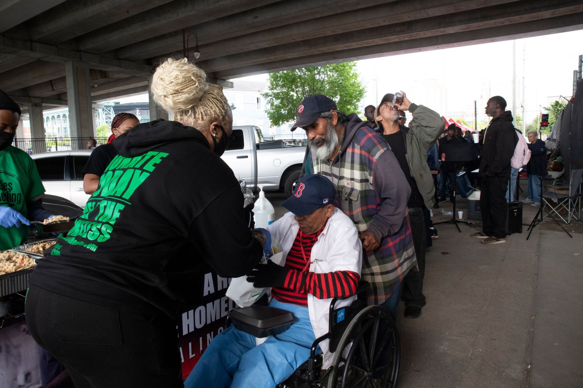 A group of people are standing around a woman in a wheelchair.