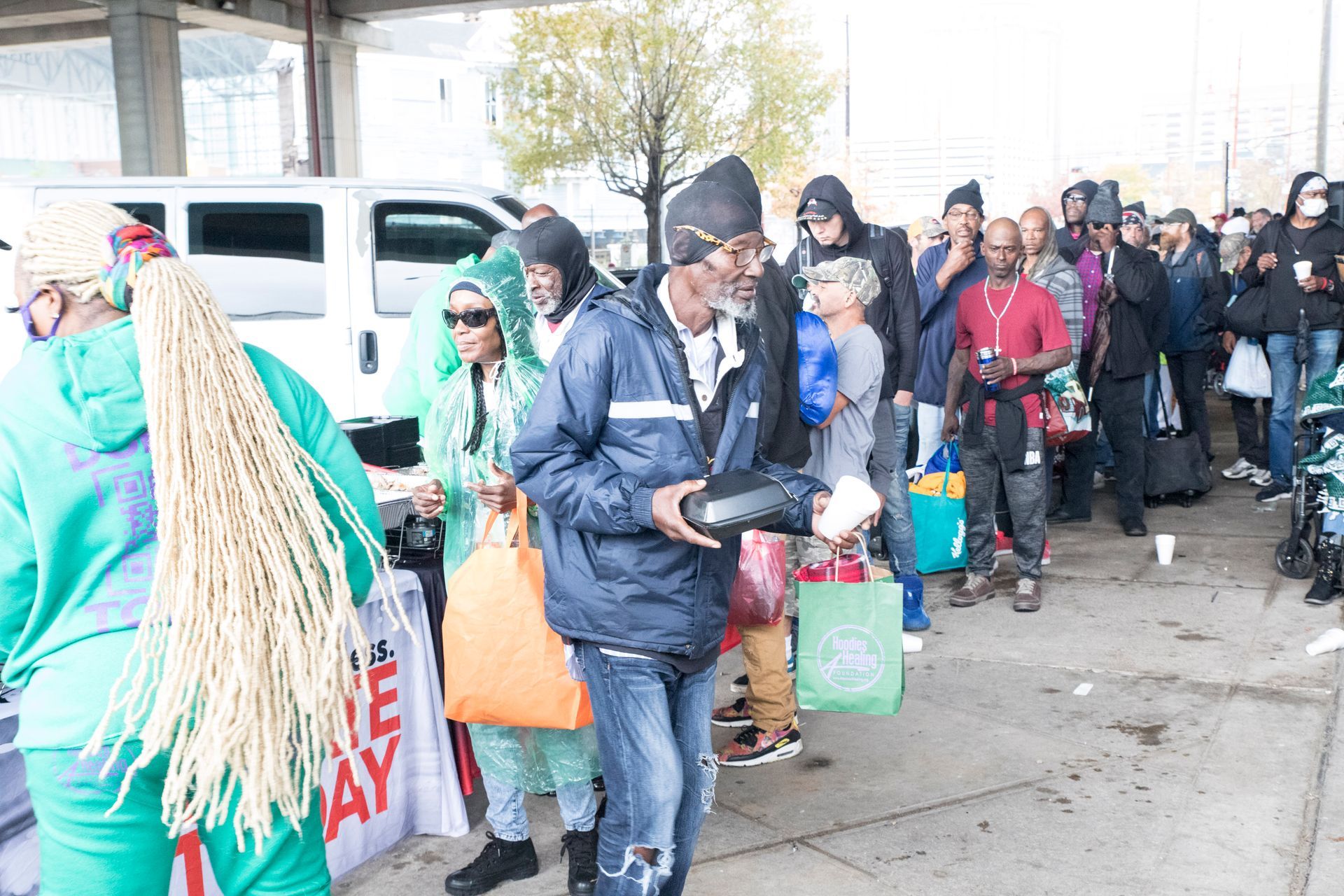 A group of people are standing in a line on the sidewalk.