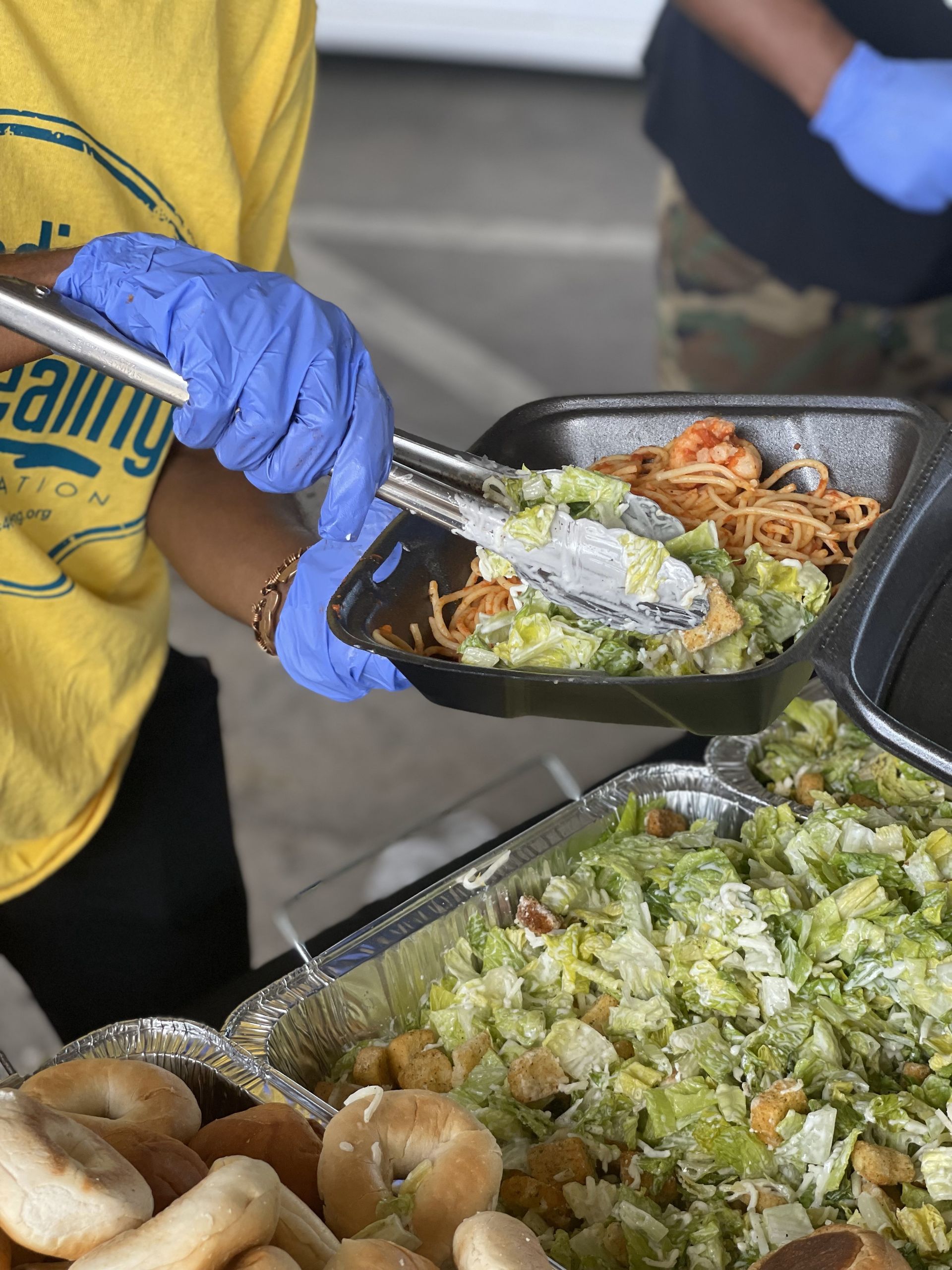 A person wearing blue gloves is serving food from a tray