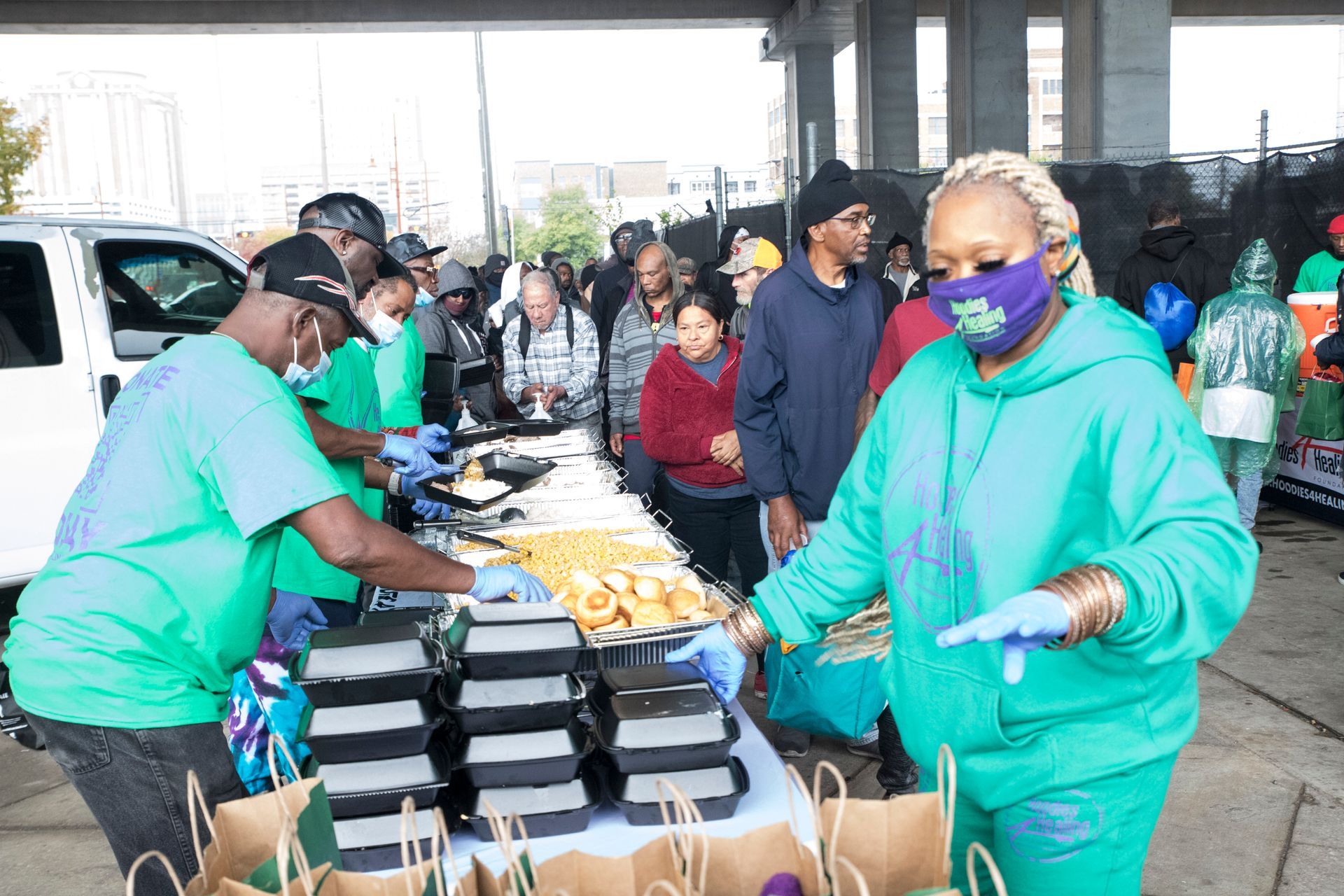 A group of people are standing around a table with boxes of food.