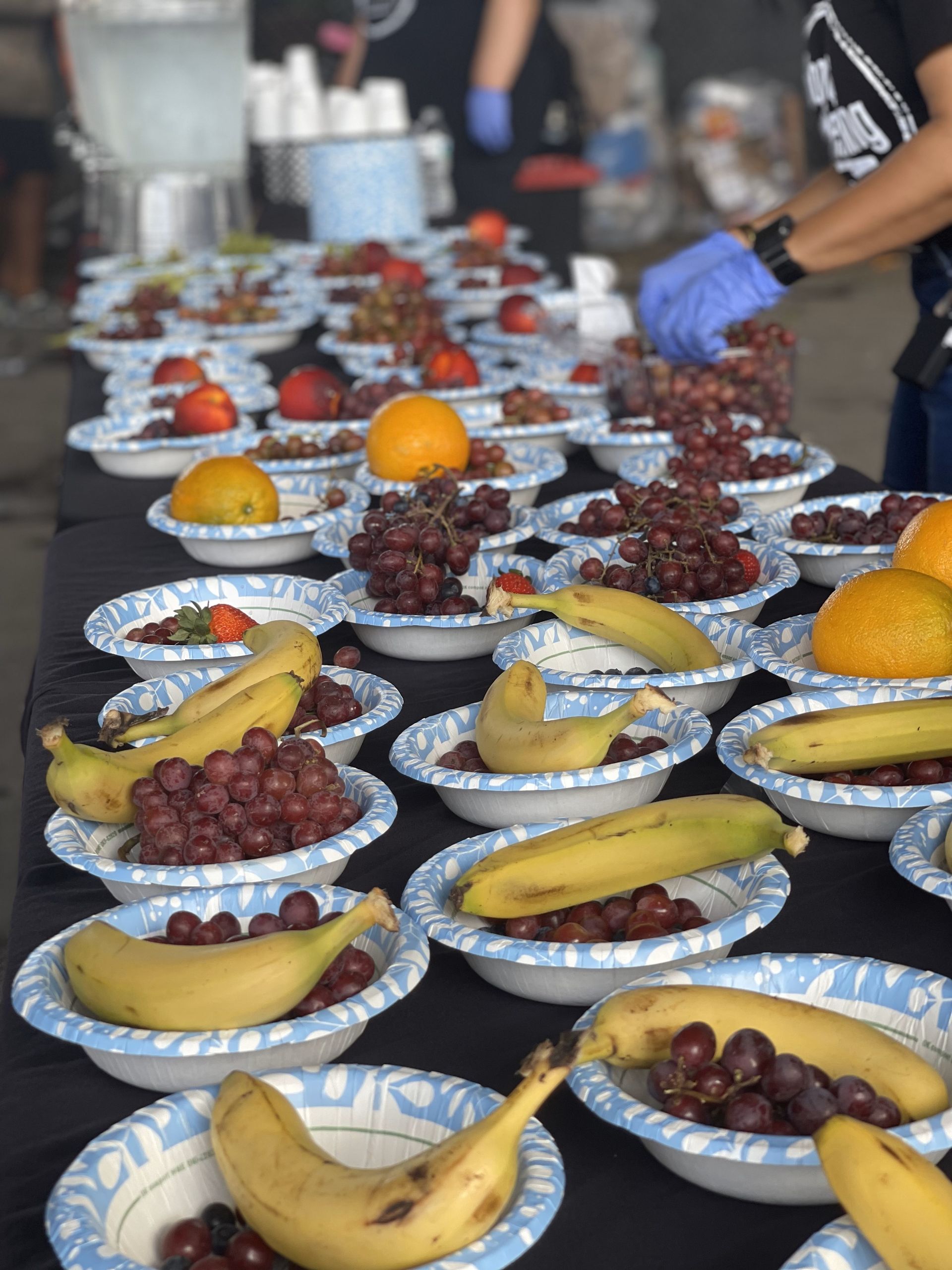 A table full of bowls of fruit including bananas and grapes