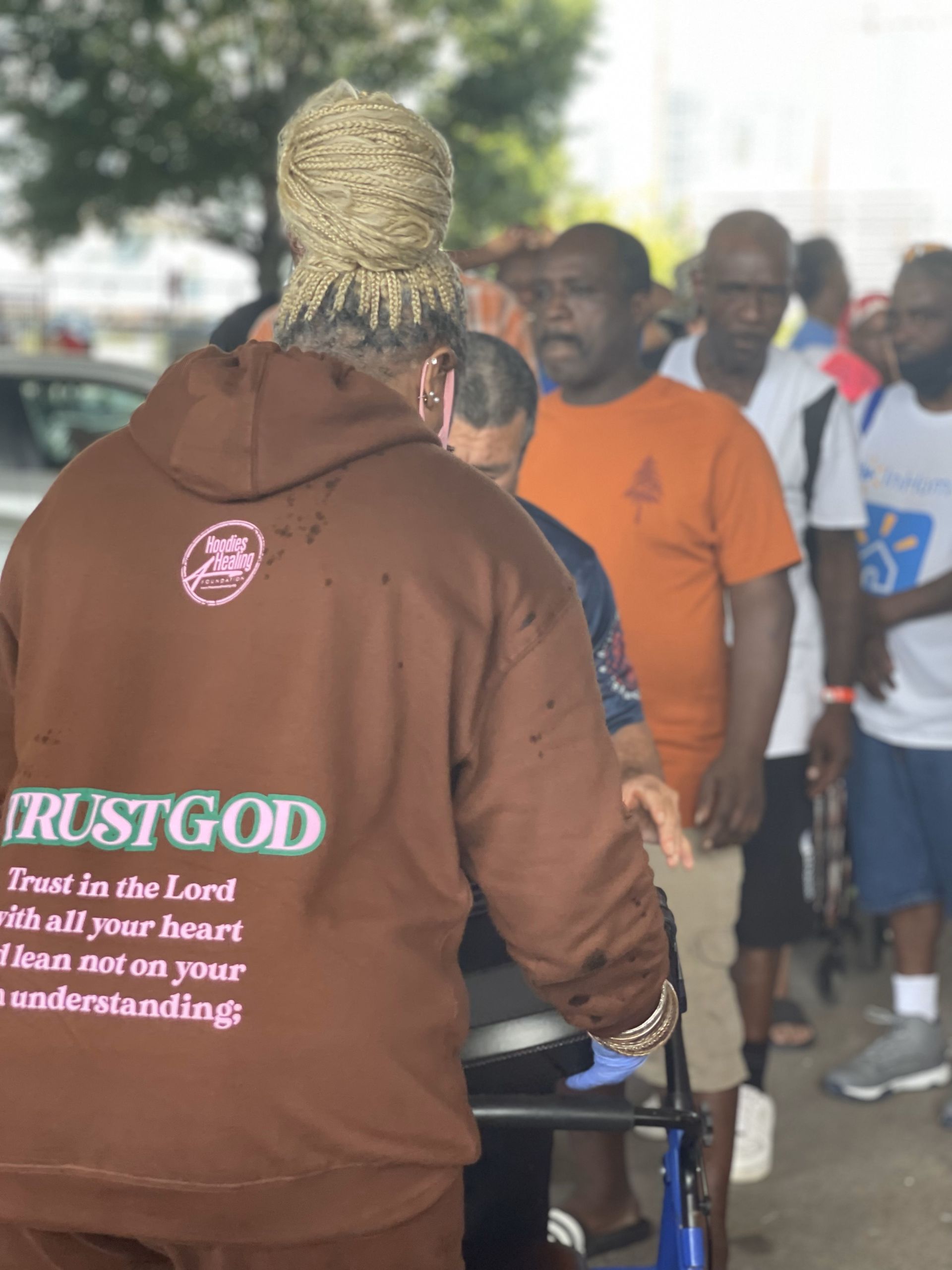 A man wearing a brown hoodie that says trust god
