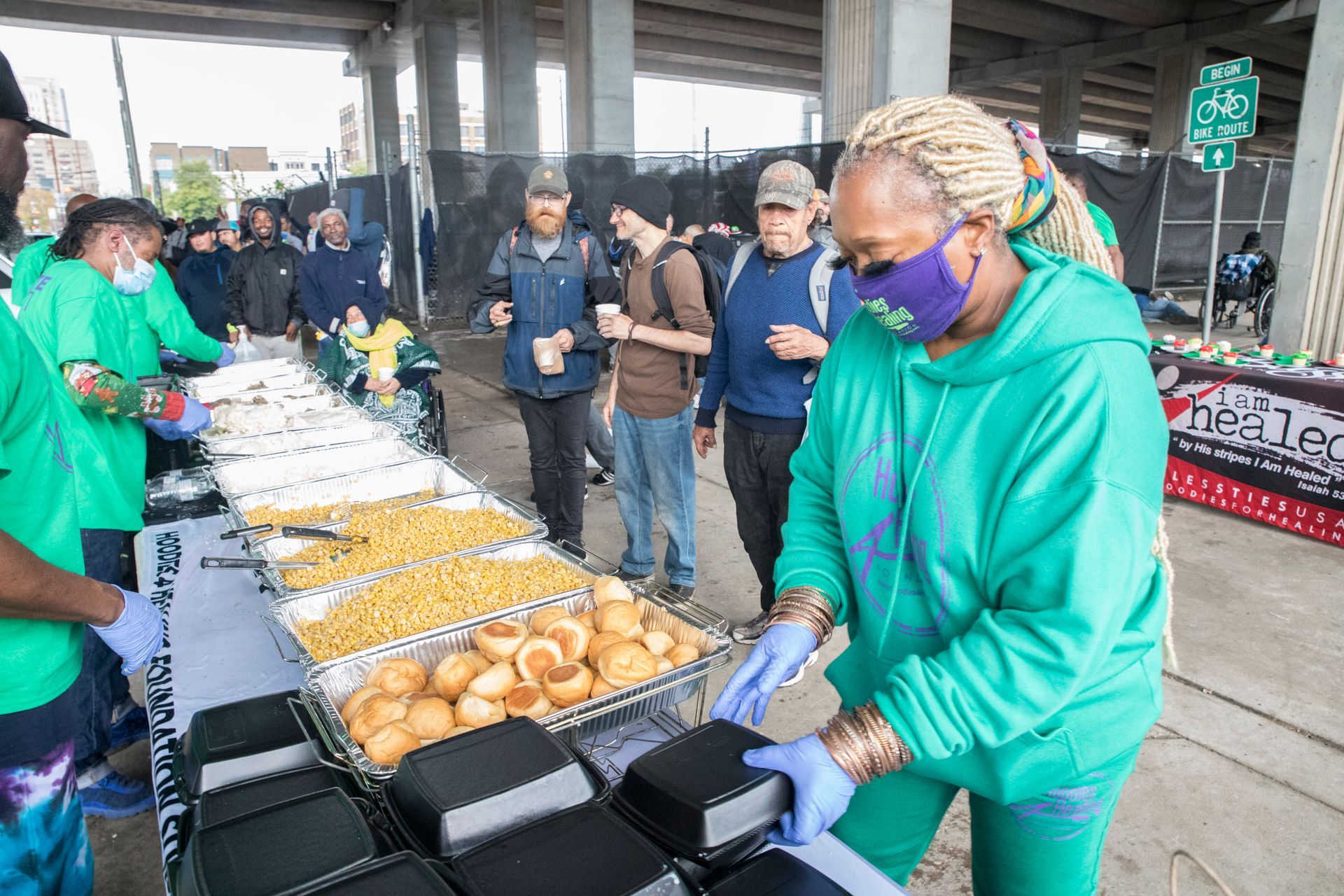 A woman wearing a mask is standing in front of a table filled with food.