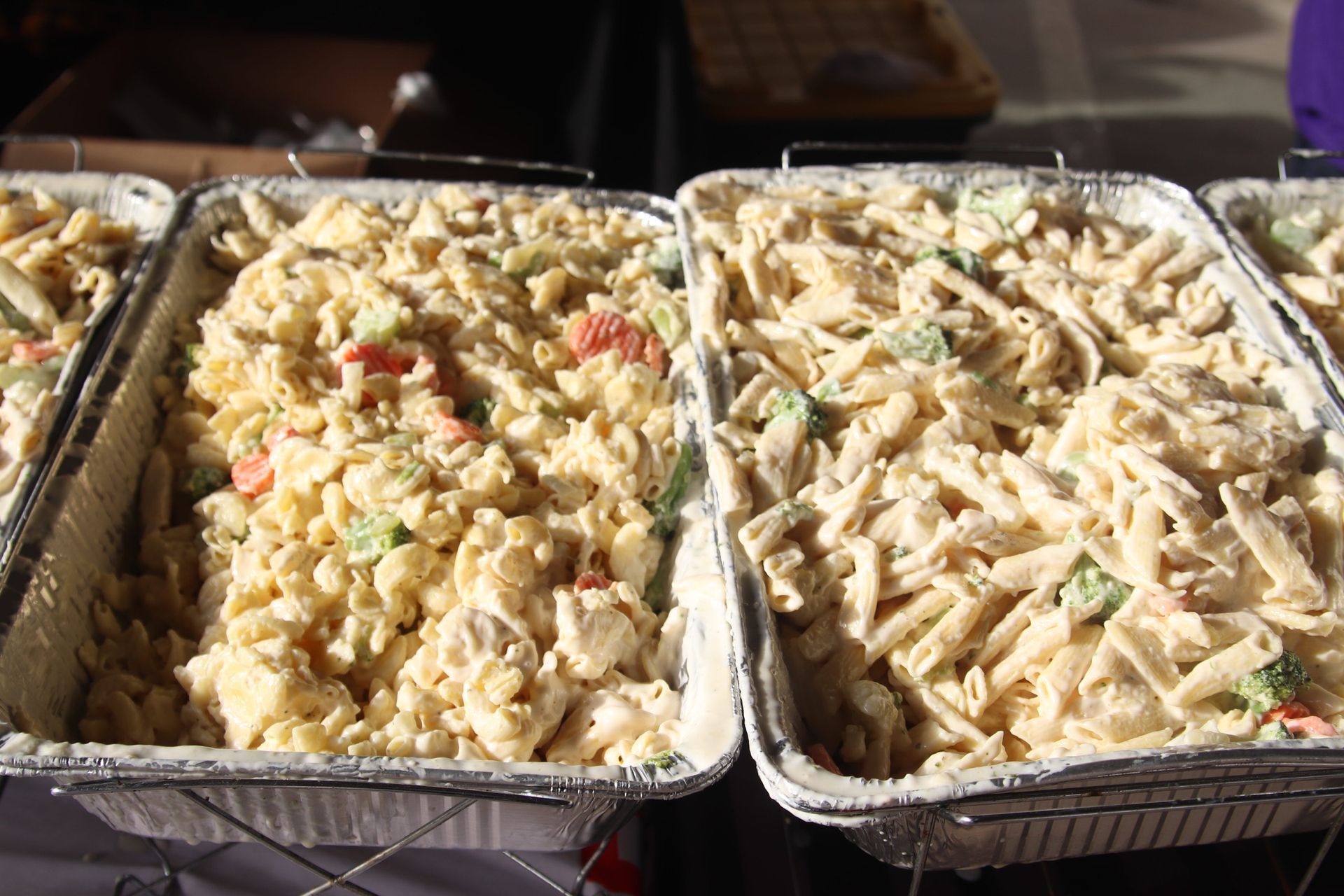 Three trays of macaroni salad are sitting on a table.