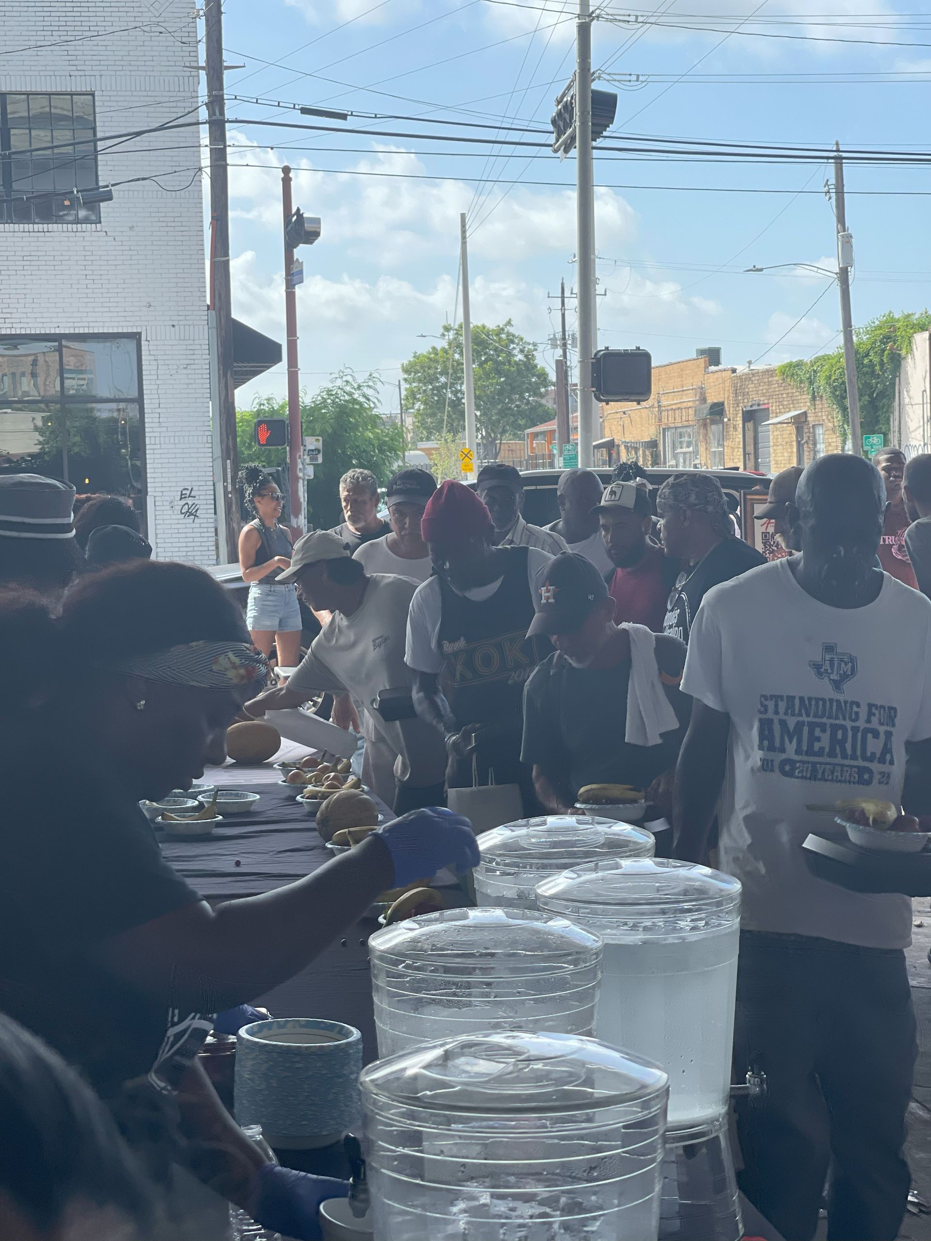 A group of people standing around a table with a man wearing a t-shirt that says texas for america