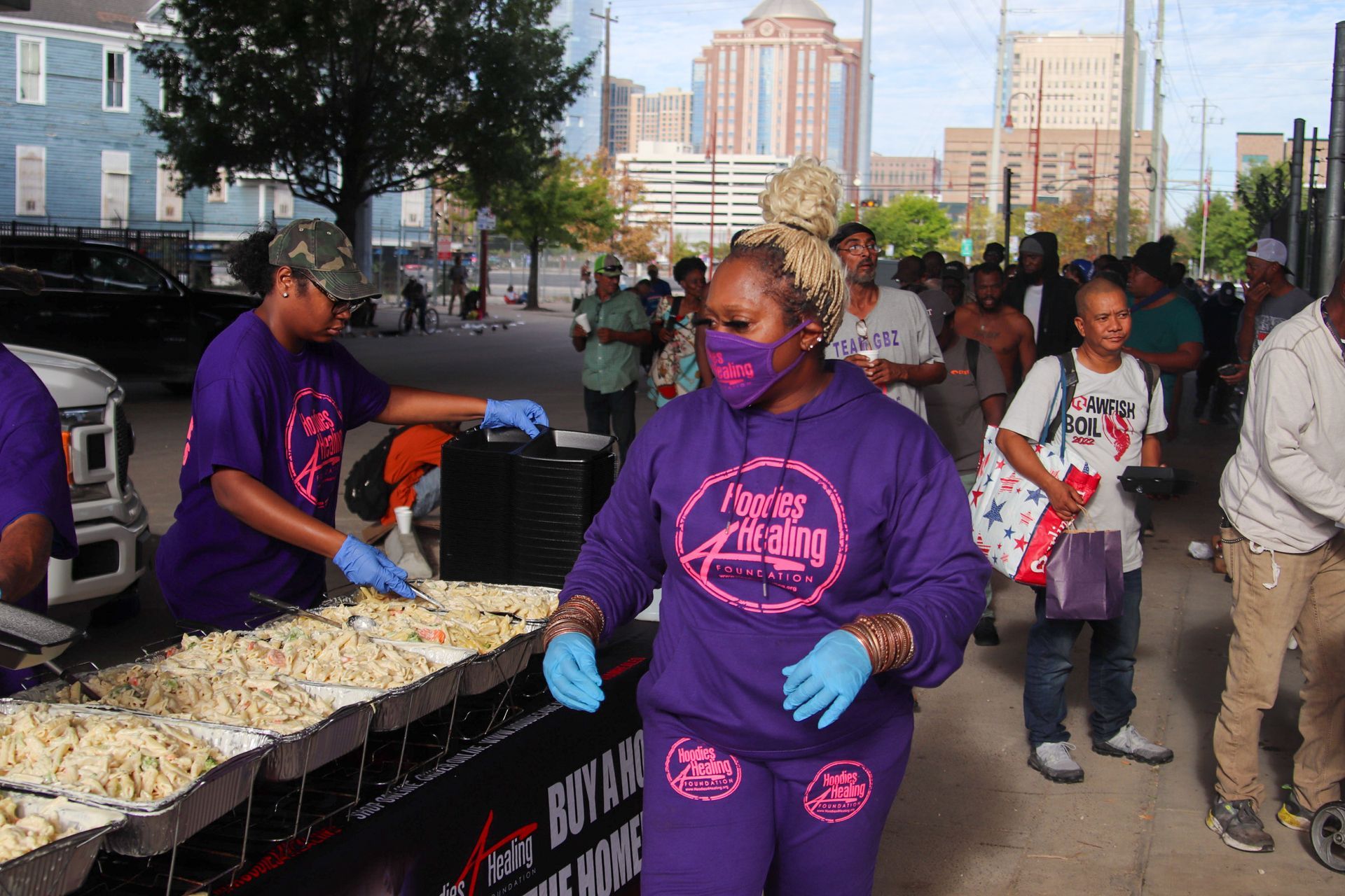 A woman wearing a mask and gloves is standing in front of a table of food.