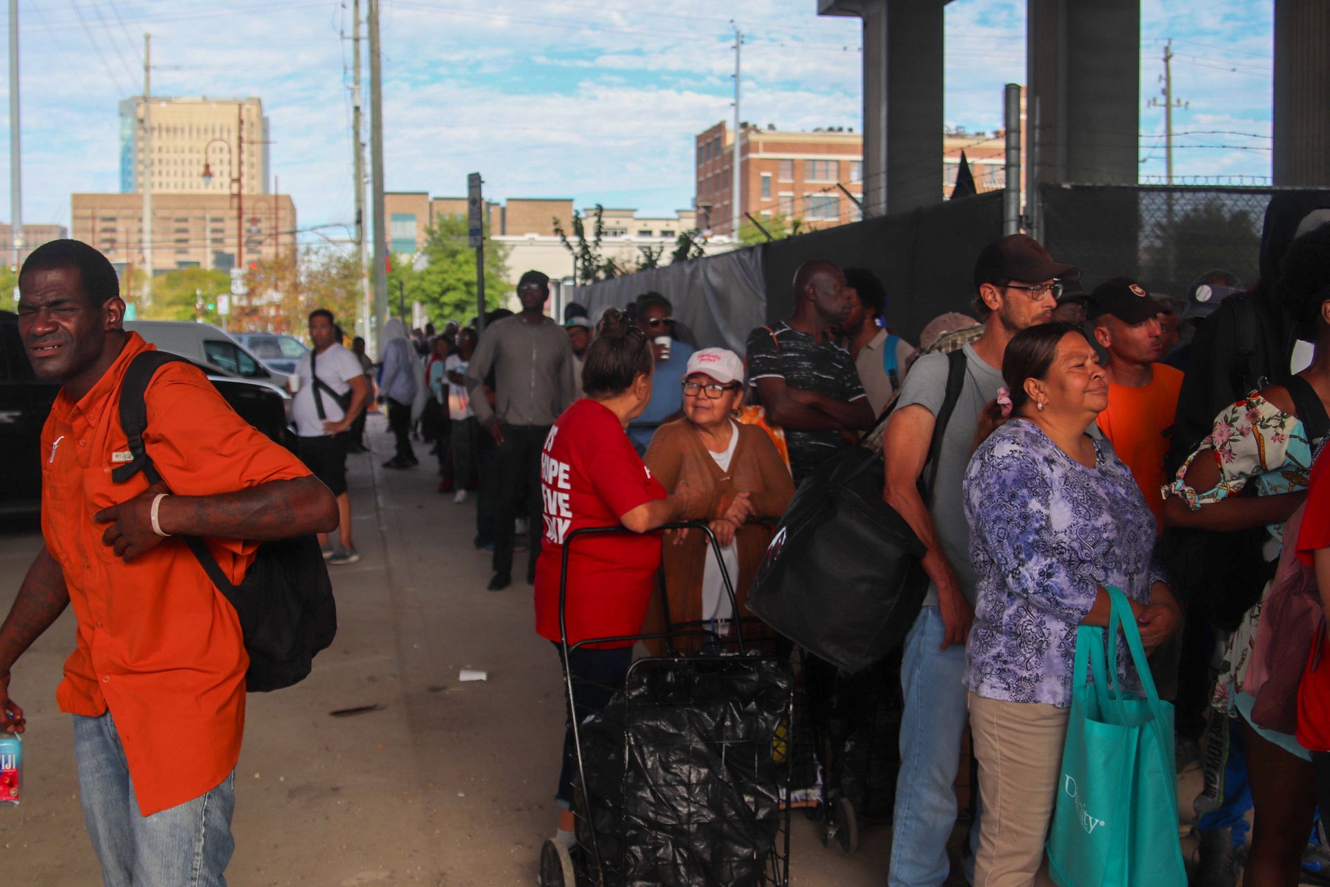 A man in an orange shirt is walking through a crowd of people