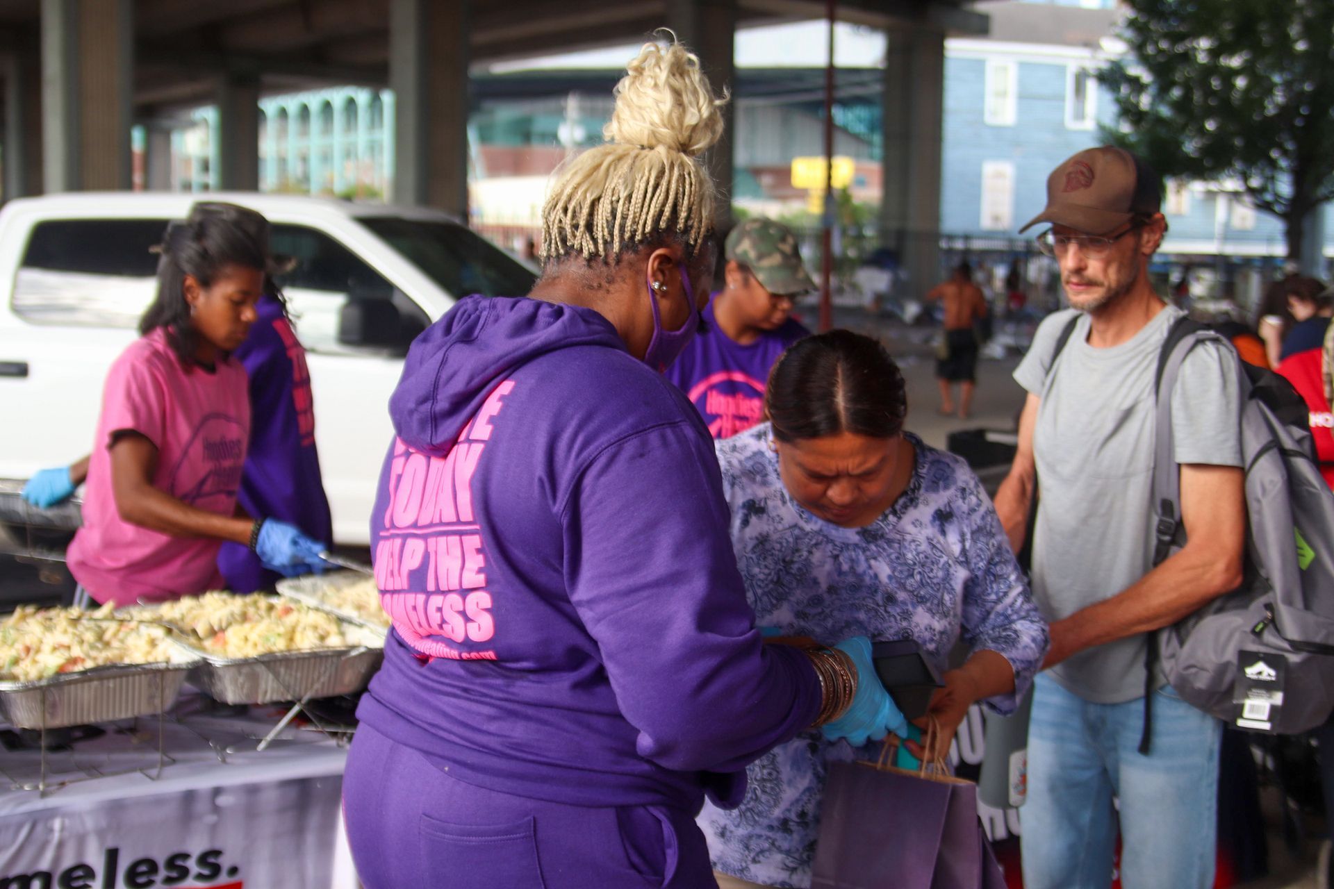 A group of people are standing around a table with food.