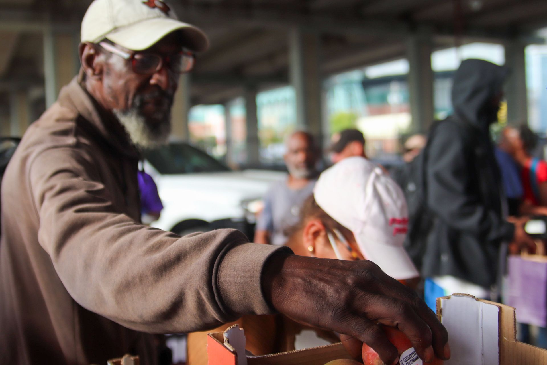 A man wearing a baseball cap is standing in front of a cardboard box.