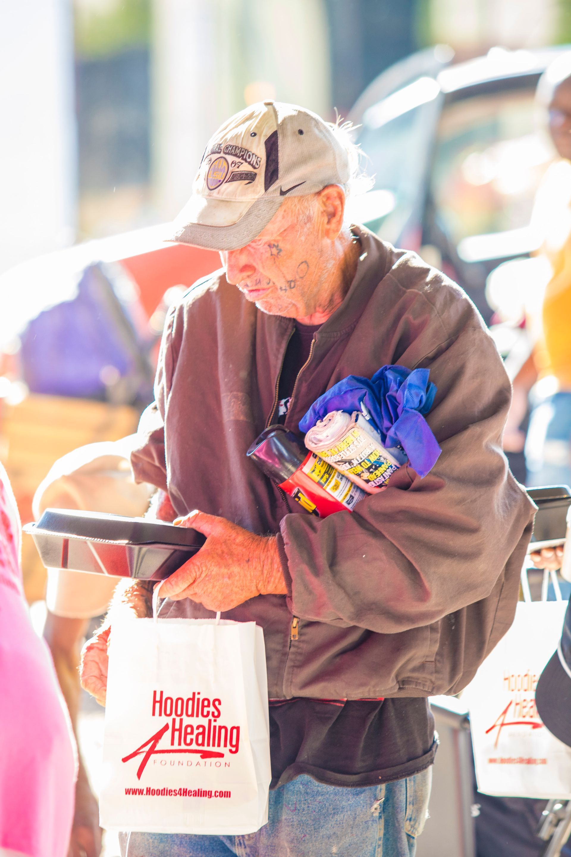 An elderly man is carrying a bag of food.