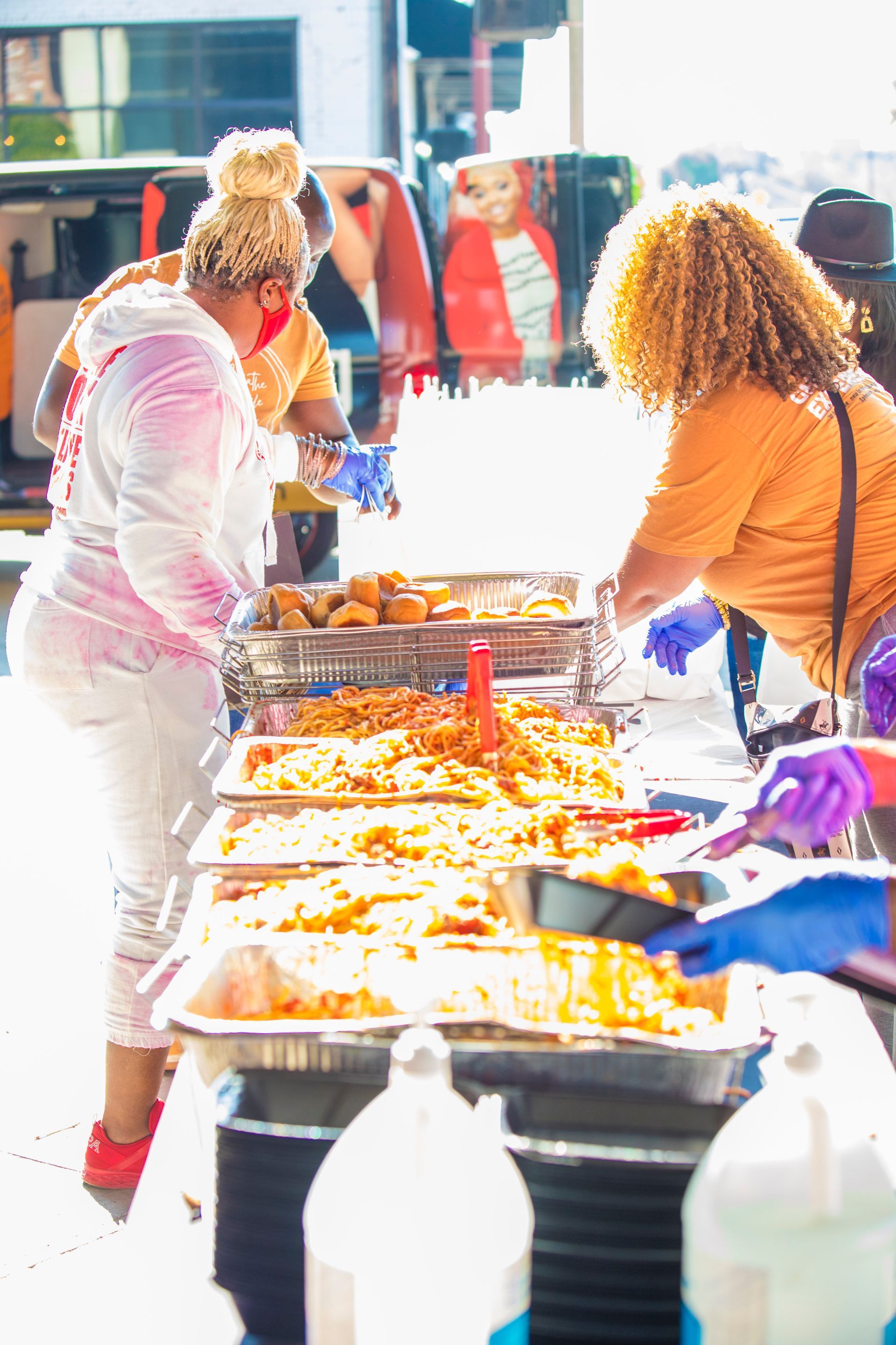 A group of women are standing around a table filled with food.