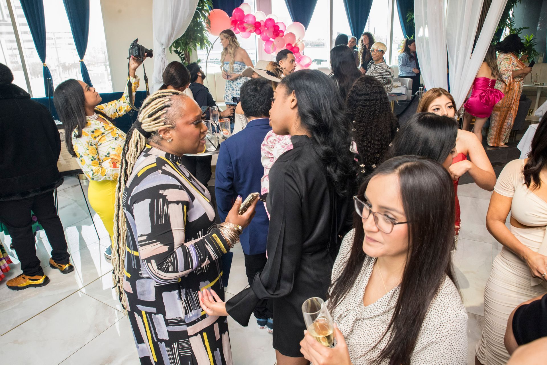 A group of people are standing in a room talking to each other.