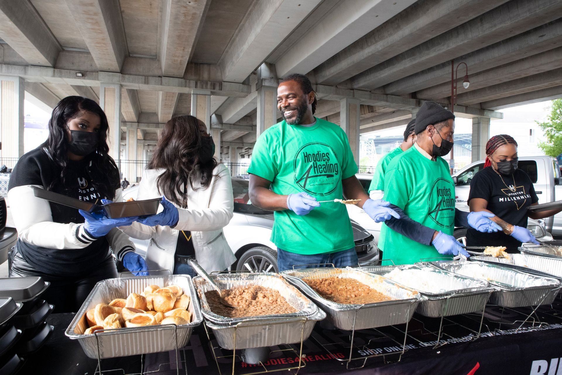 A group of people are standing around a table serving food.