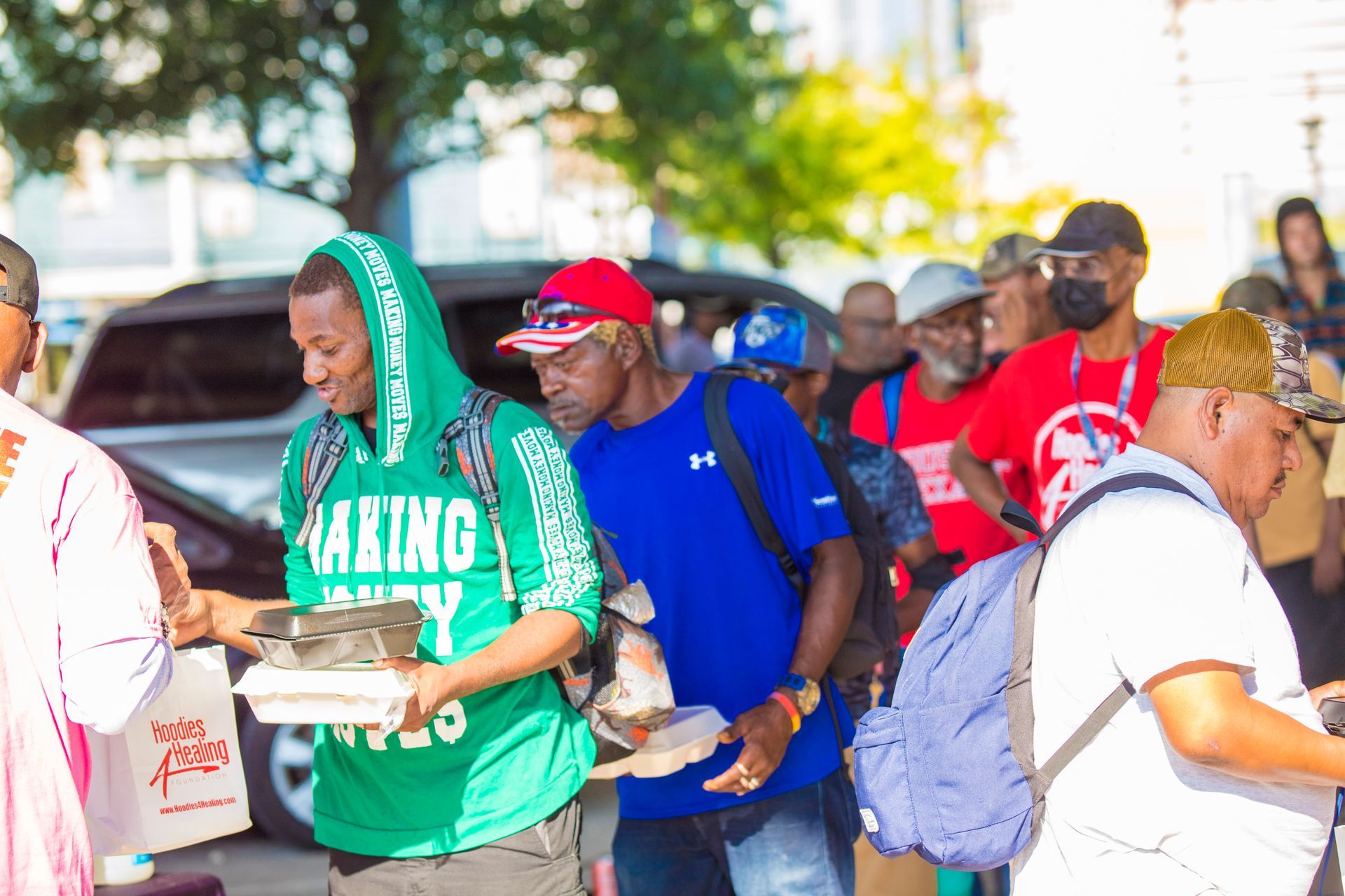 A group of people are standing in a line holding plates of food.