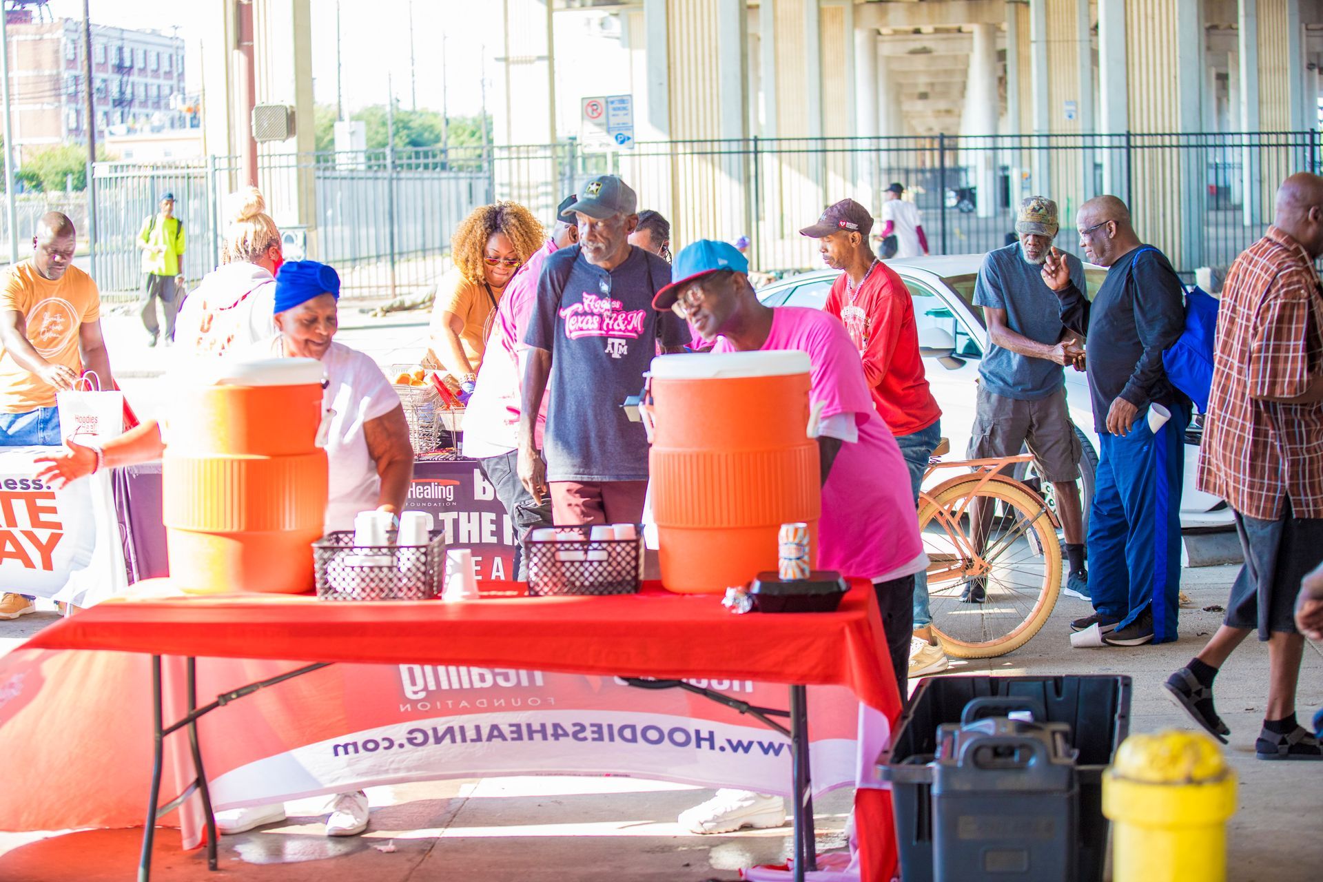 A group of people are standing around a table with coolers on it.