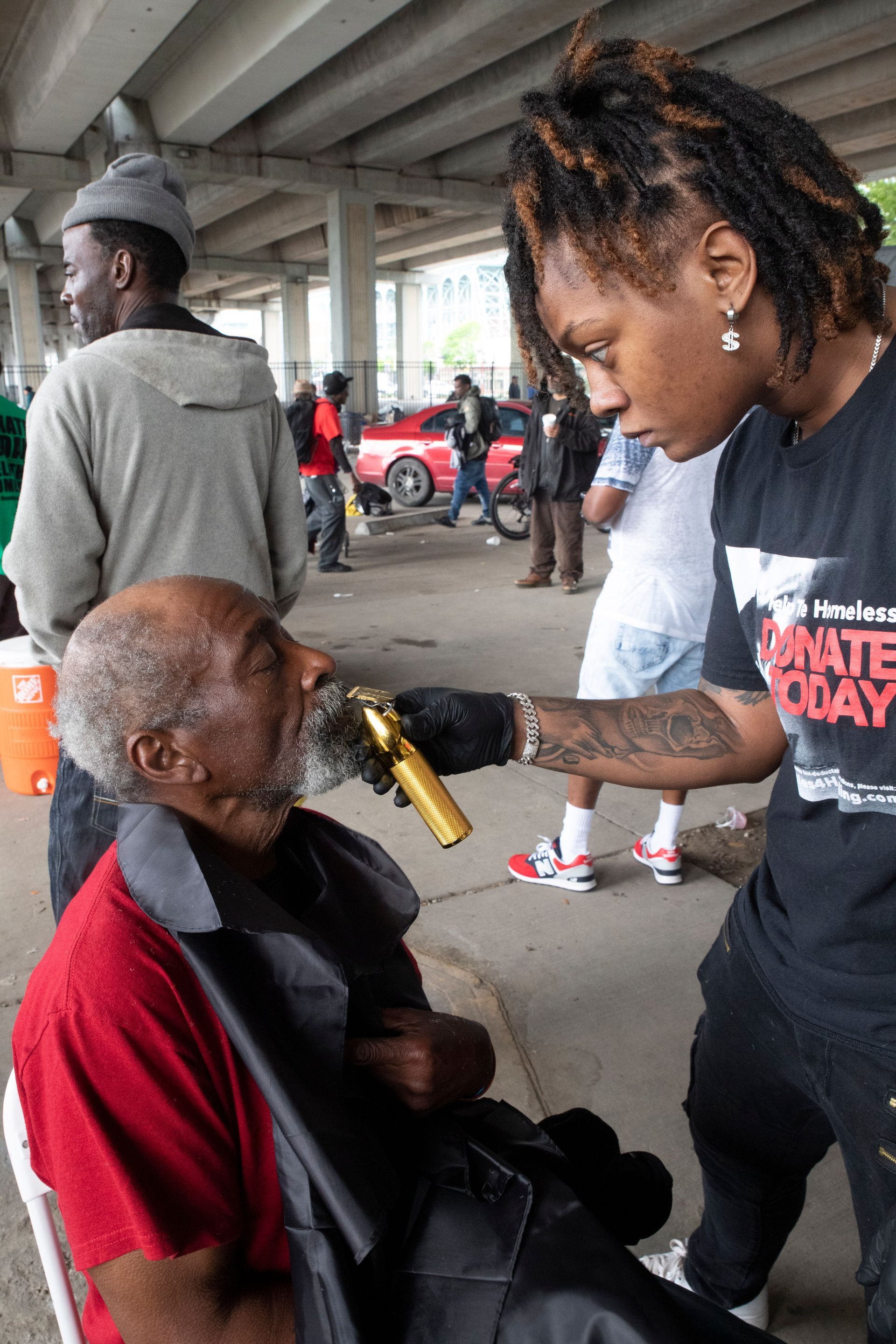 A man in a wheelchair is getting his beard shaved by a woman.