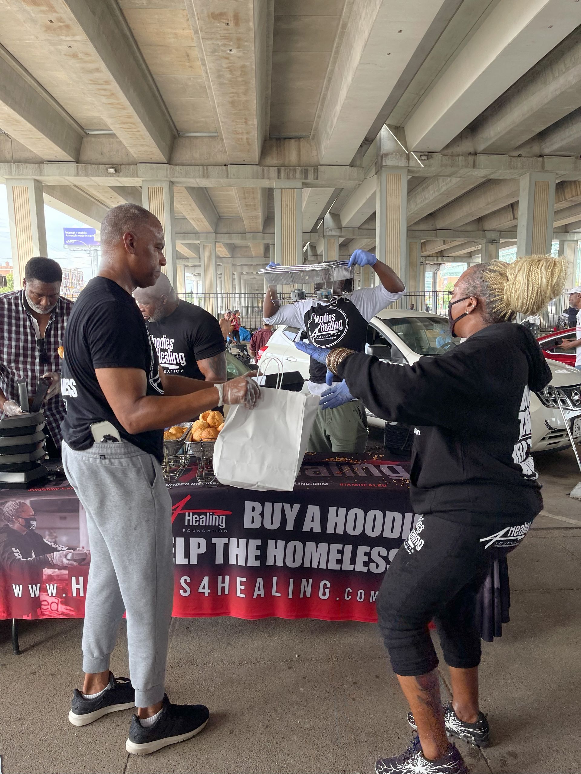 A group of people are standing around a table with a sign that says buy a hoodie