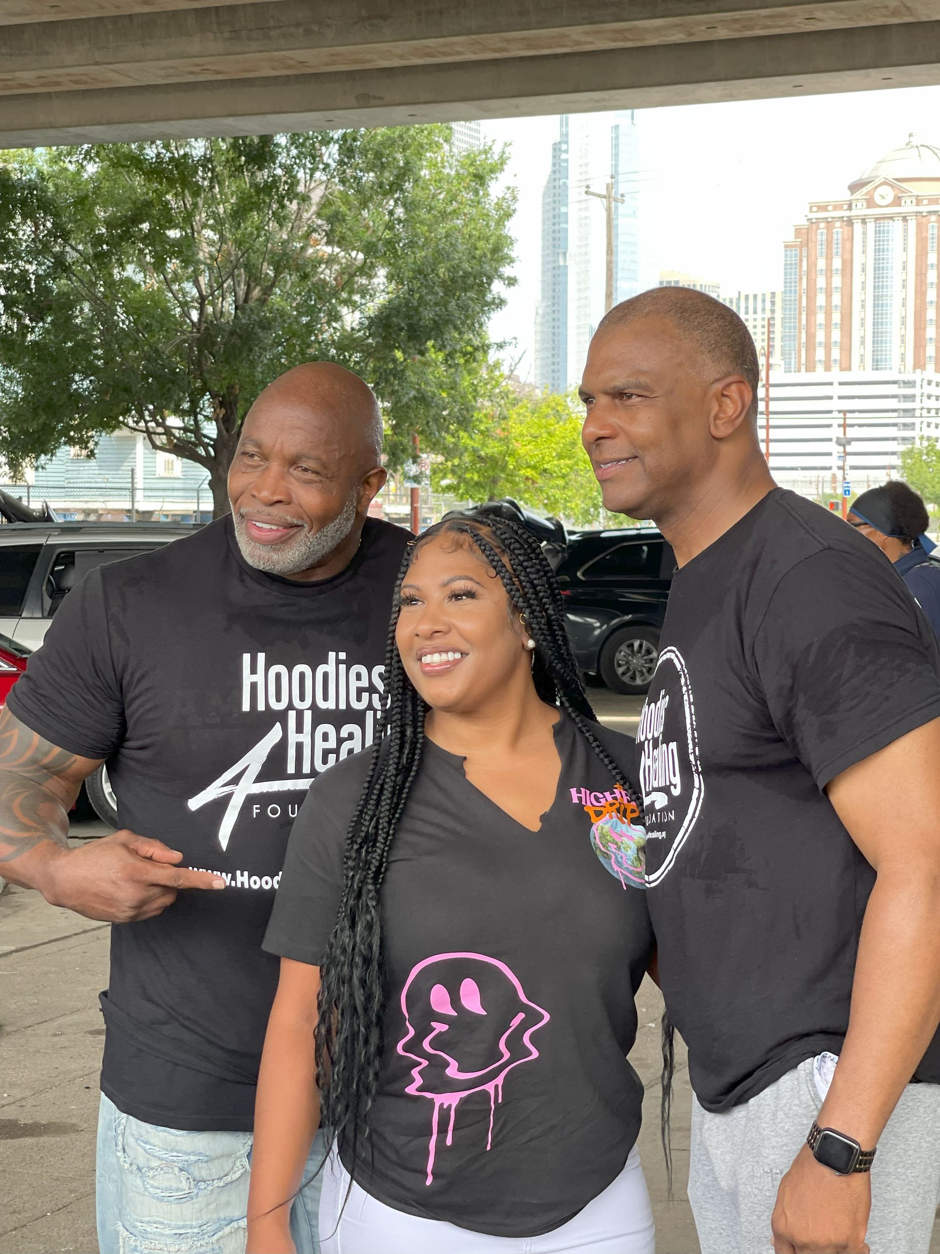 Three men and a woman are posing for a picture in a parking lot.