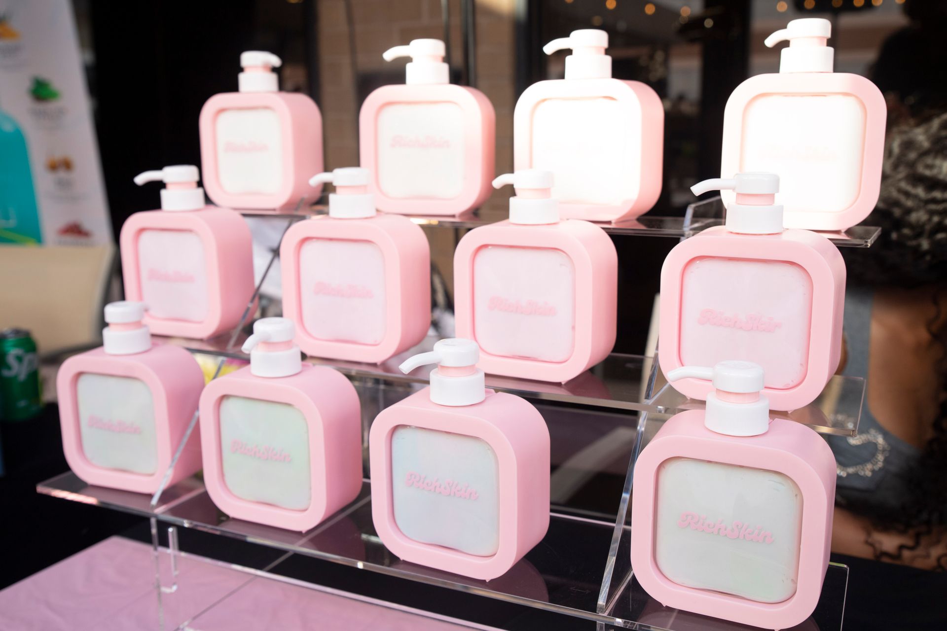 A bunch of pink bottles sitting on top of each other on a shelf.