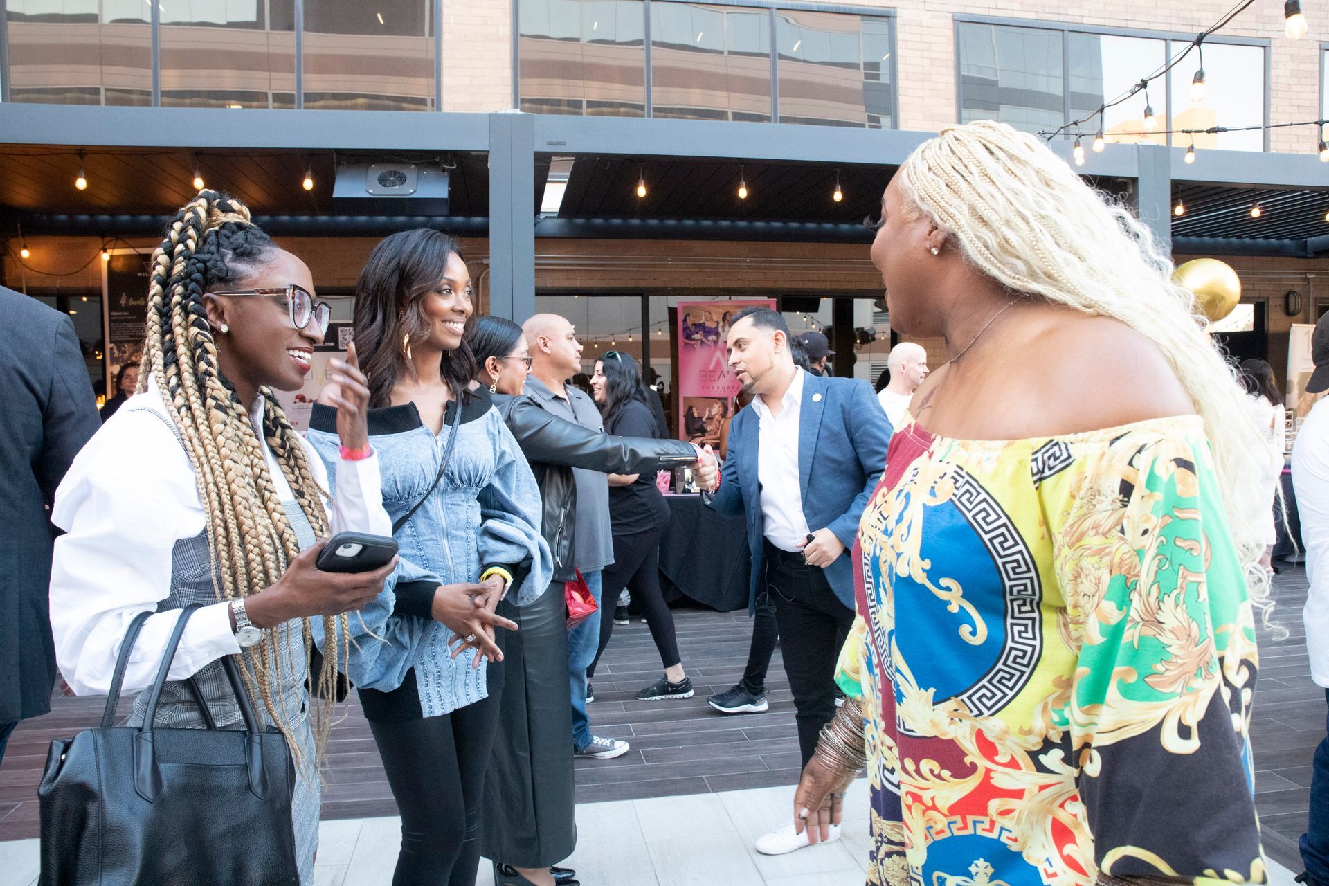 A group of women are standing in front of a building talking to each other.