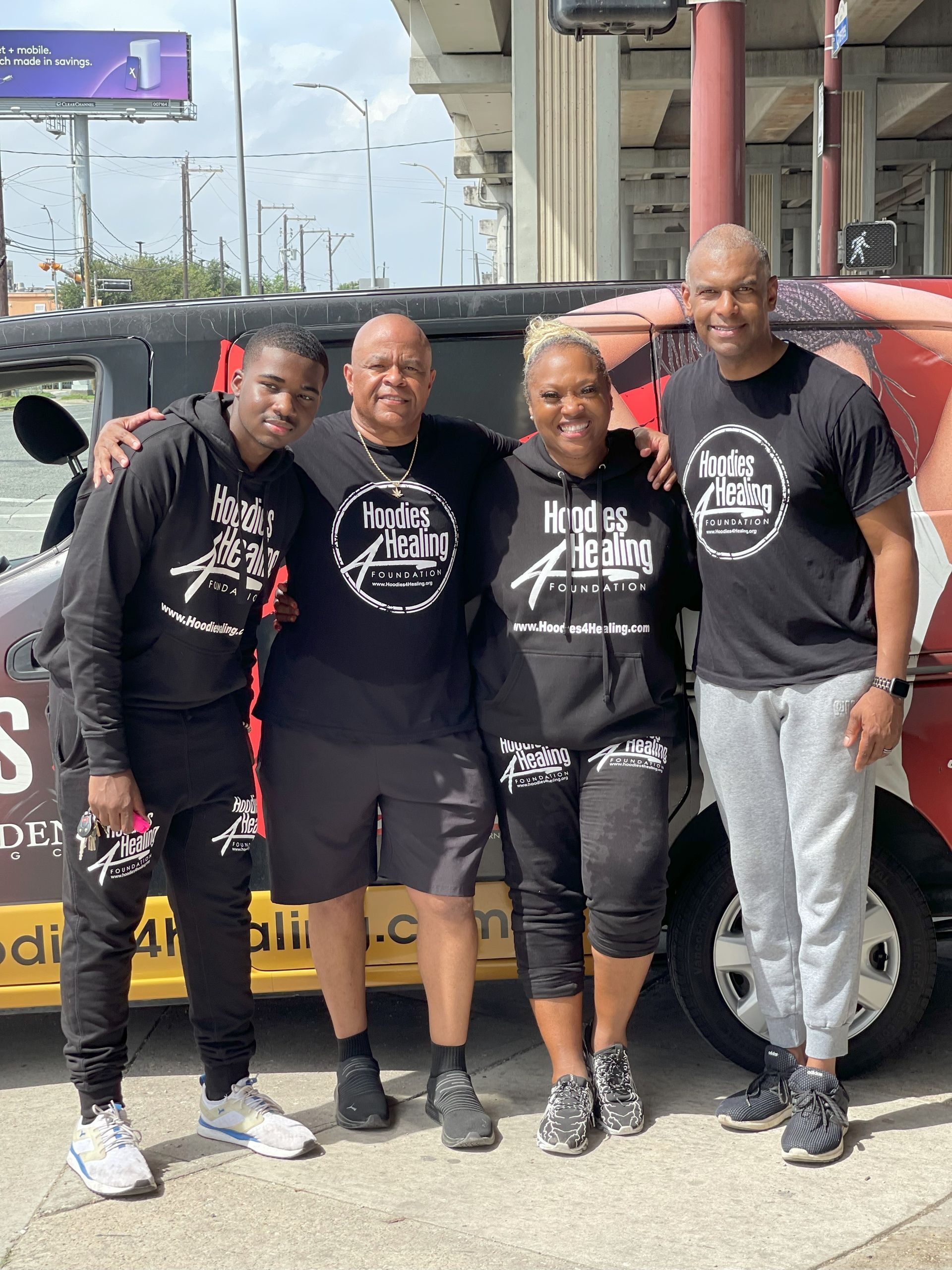 A group of people are posing for a picture in front of a van.